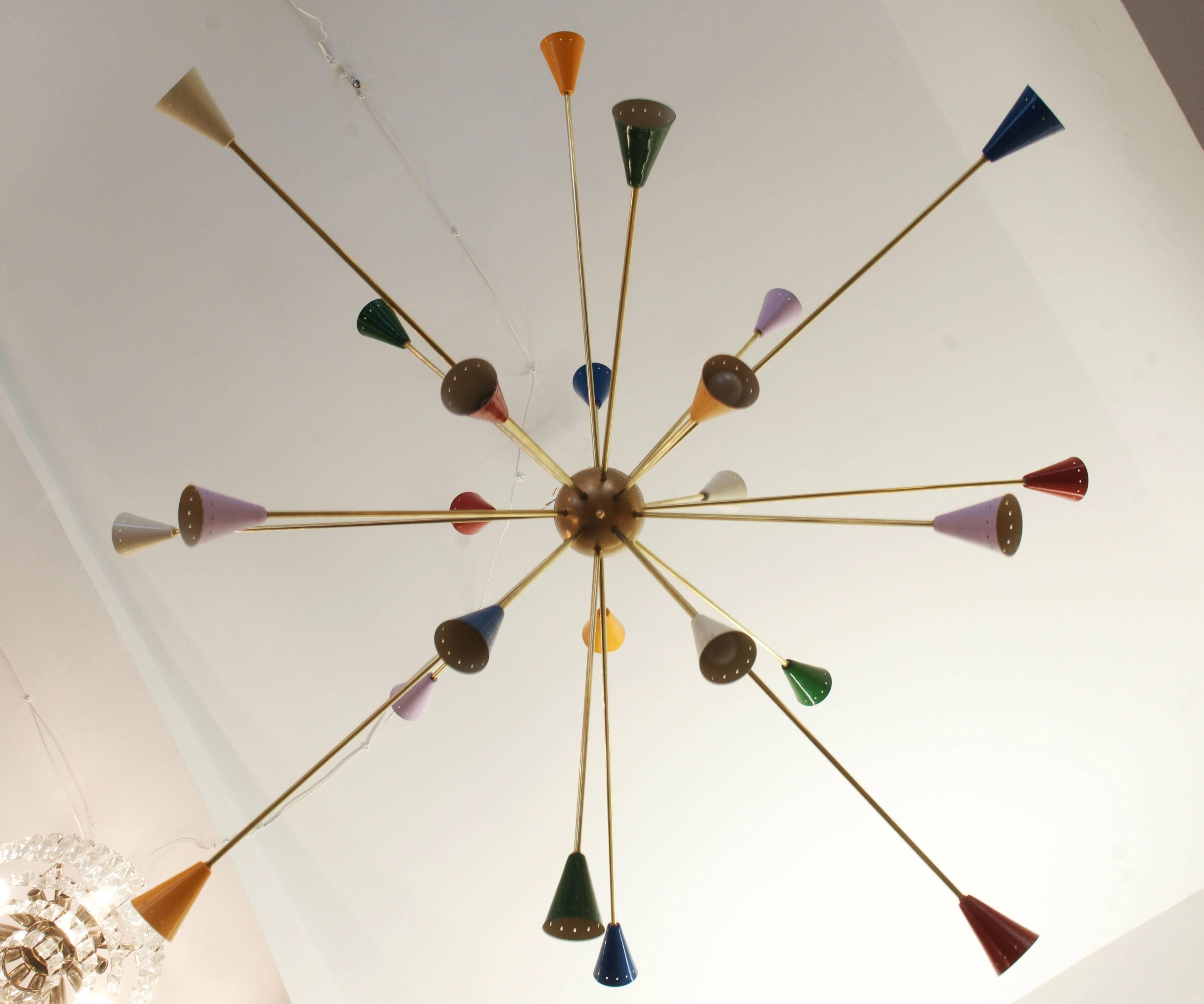 Huge brass construction with 24 arms in different lengths and aluminum cones on the ends painted in different colors, 24 porcelain E14 sockets for max. 40W bulbs or LED bulbs. 
In the style of Stilnovo, Italy from the 1950s.
Dimensions:
Diameter