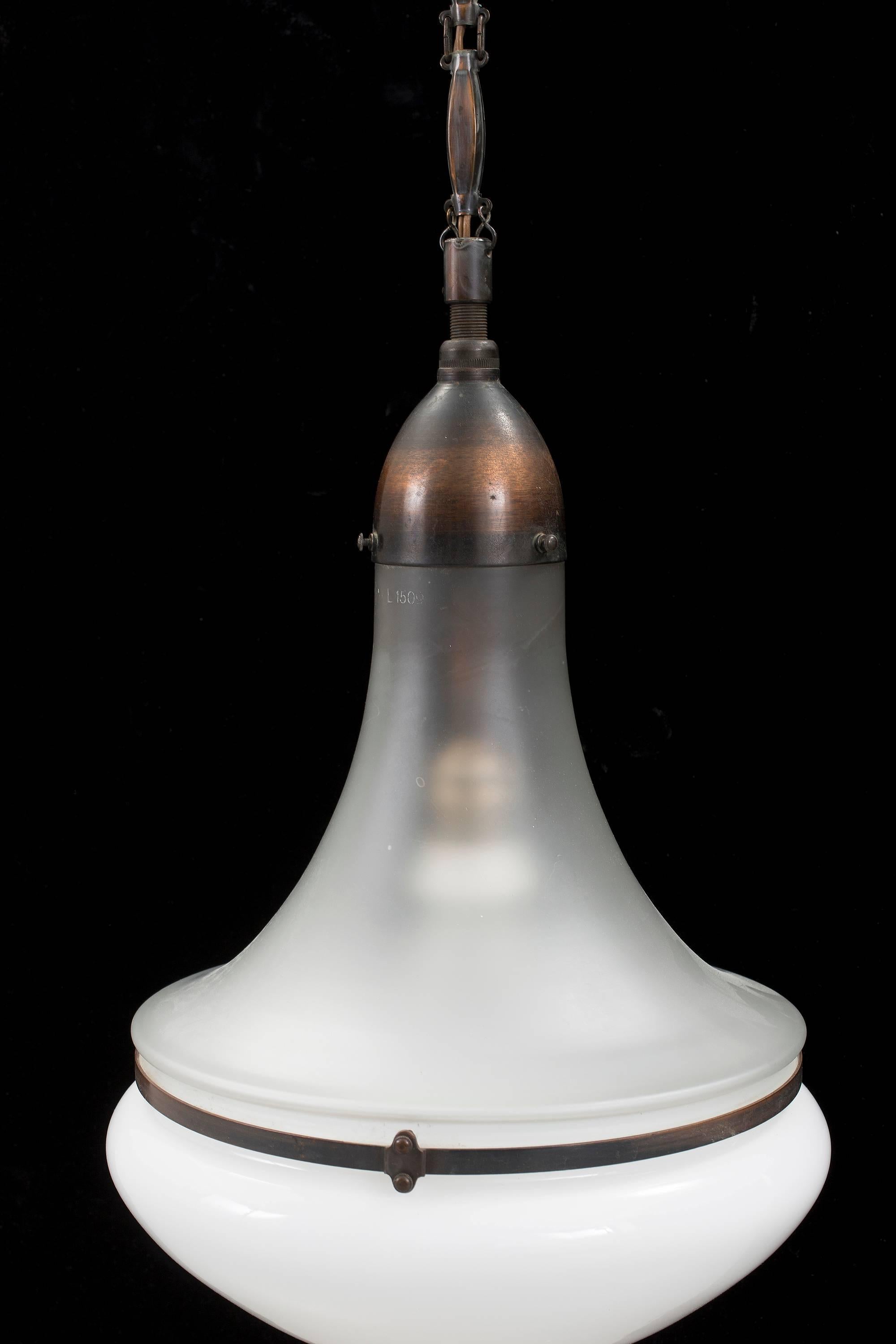 The pendant was designed by Peter Behrens in 1908 for Siemens.
This lamp is complete original with a nice combination of an opaline glass lower shade and a frosted clear glass upper shade.
All metal/copper parts are complete and original.
Perfect