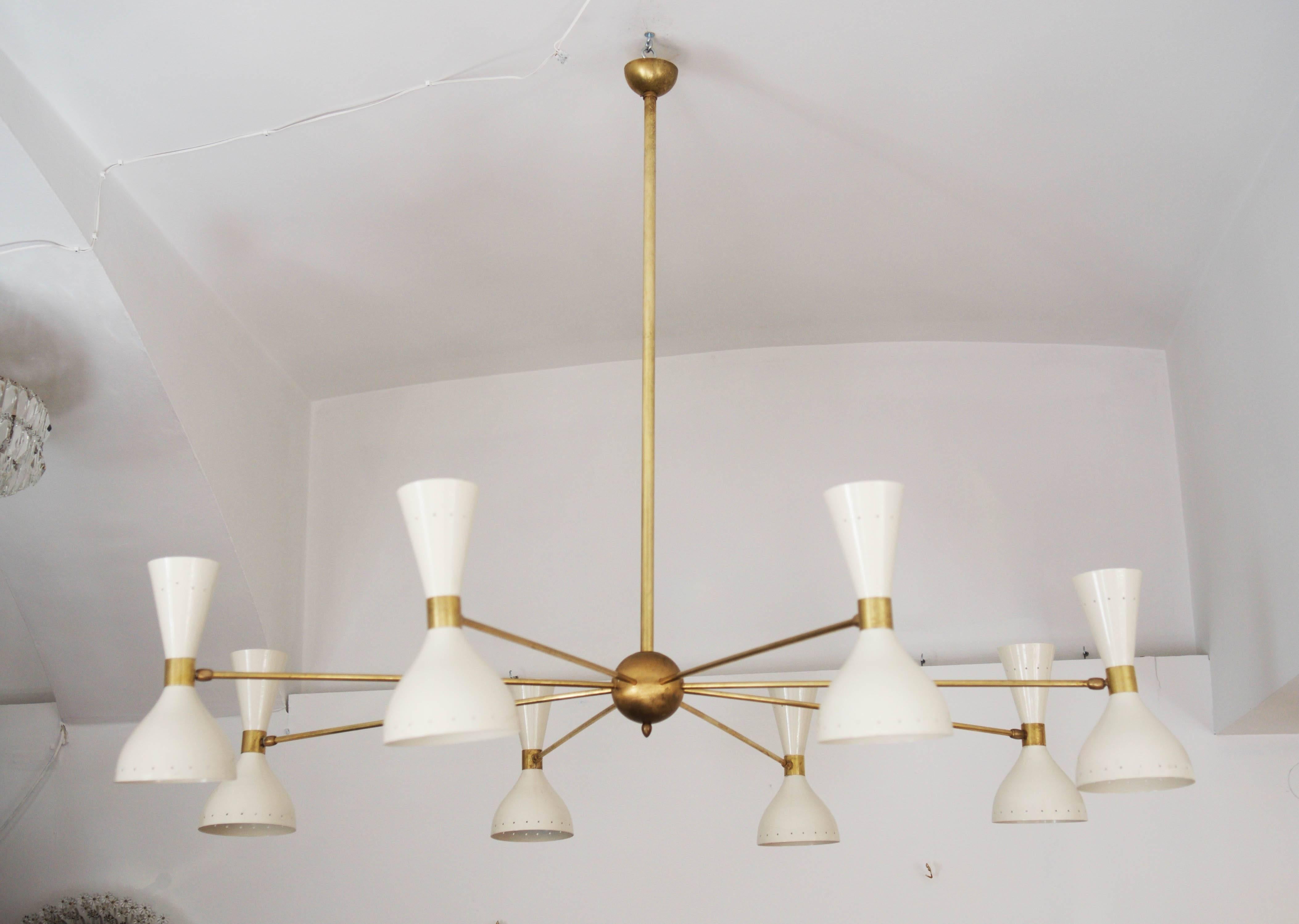Mid-Century huge spider chandelier made in Italy in the 1950s style of Stilnovo. 
Brass downrod and eight arms ending in adjustable white lacquered double cone shades, each with up and down shining lights, fitted with porcelain E14 sockets.
up to