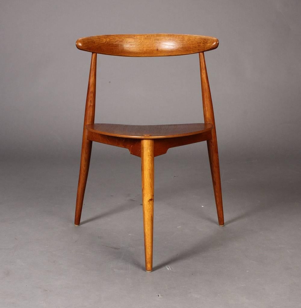 Hans J. Wegner stackable ‘heart’ tripod chairs, the seat of form bends veneered teak frame and top rail of oak. Designed in 1952. Produced by Fritz Hansen, model FH 4103. 
Literature. Noritsugu Oda: 'Danish Chairs' p. 118. 
Signs of natural patina.