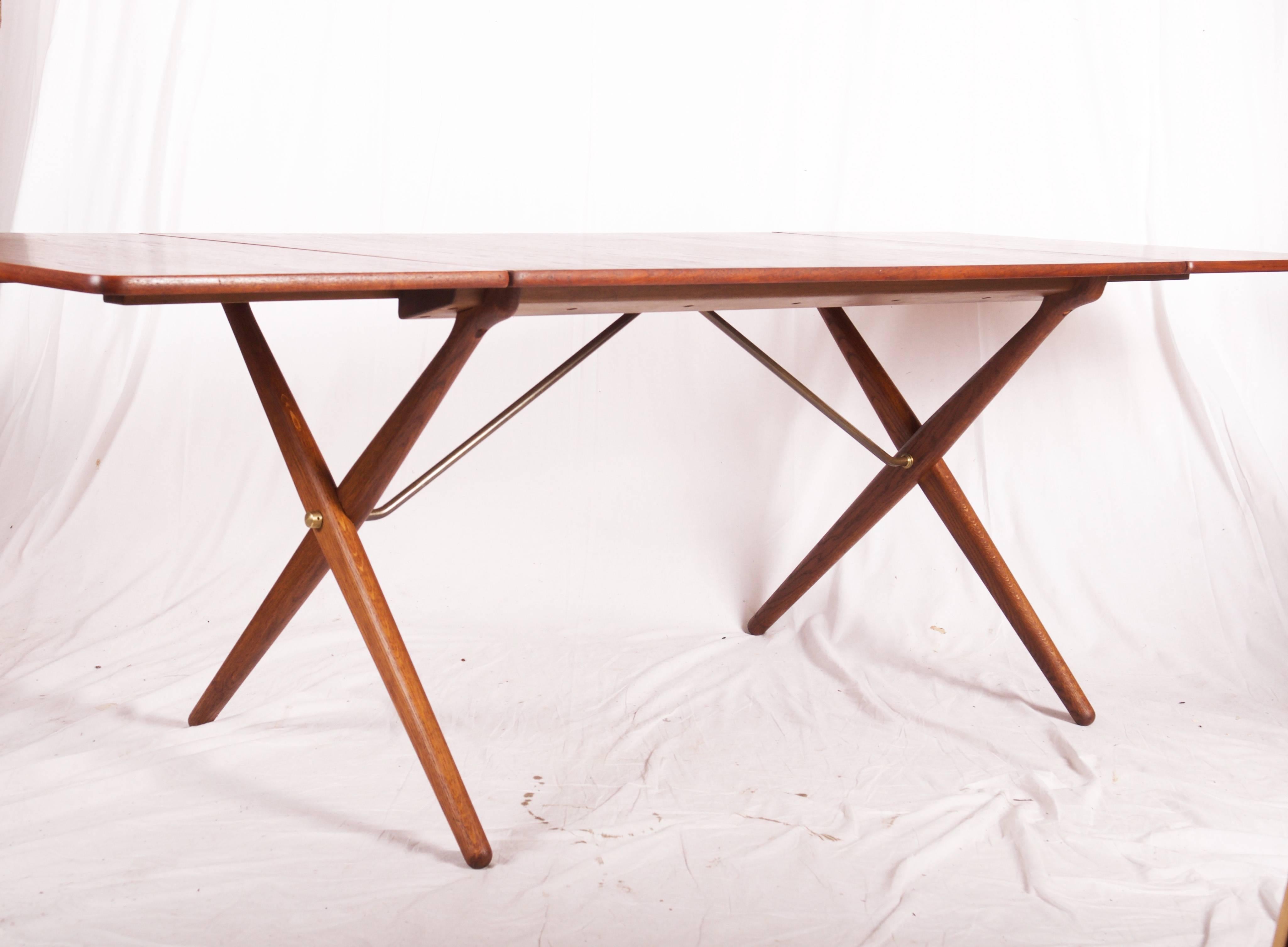 Dining table by Hans J. Wegner designed in 1952 and manufactured by Andreas Tuck, Model AT-309. Mention in catalog 1952. Cross-legs in solid oak with brass trust base. Tabletop in teak. (Max. length 228 cm. about 90