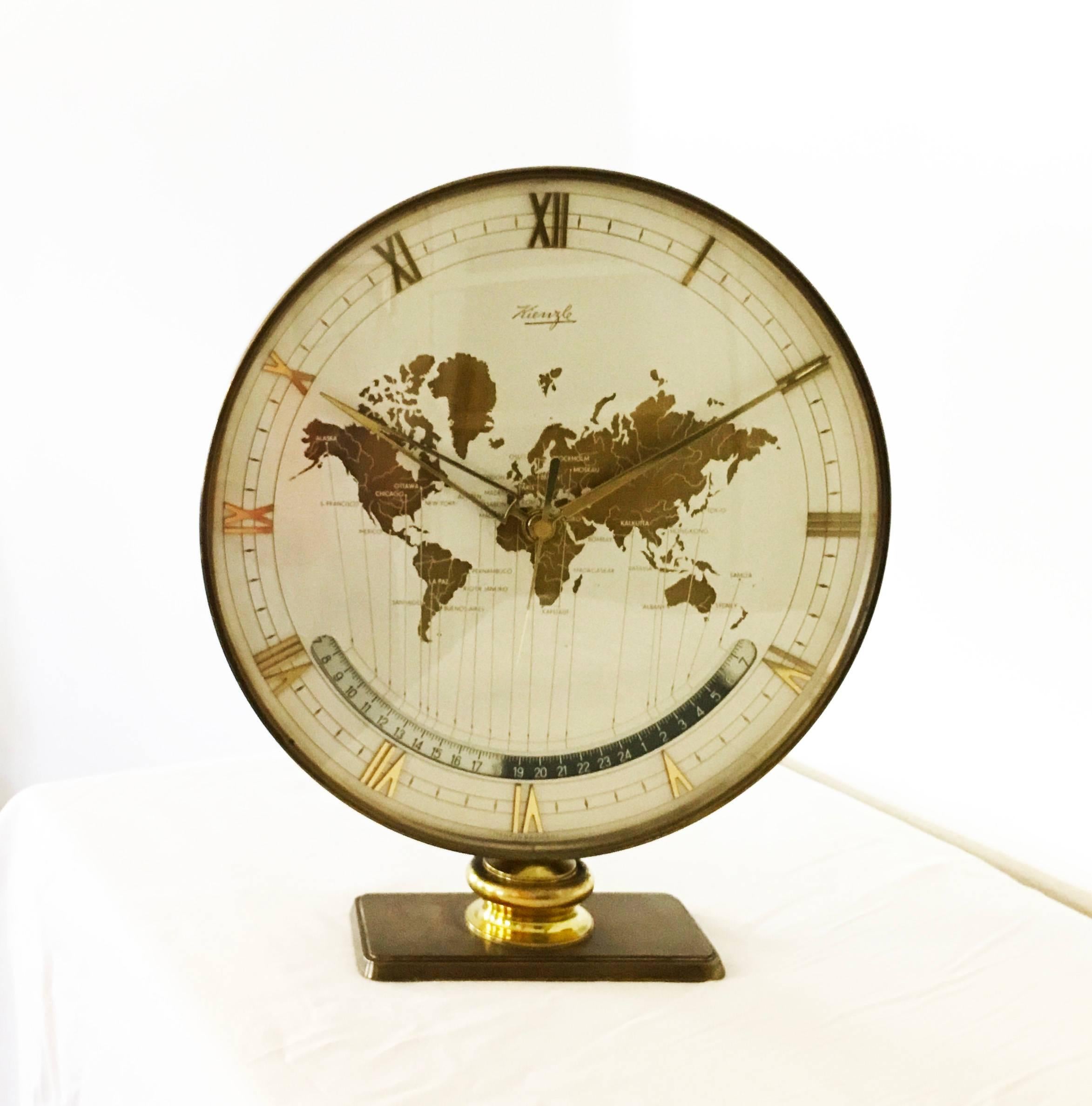 Kienzle automatic world timer zone clock.
An exclusive big table clock from Ø 26cm wonderful clocks face with world map and world time zones, glass, the heavy case and base are of solid brass. 
Original condition but the mechanical movement was