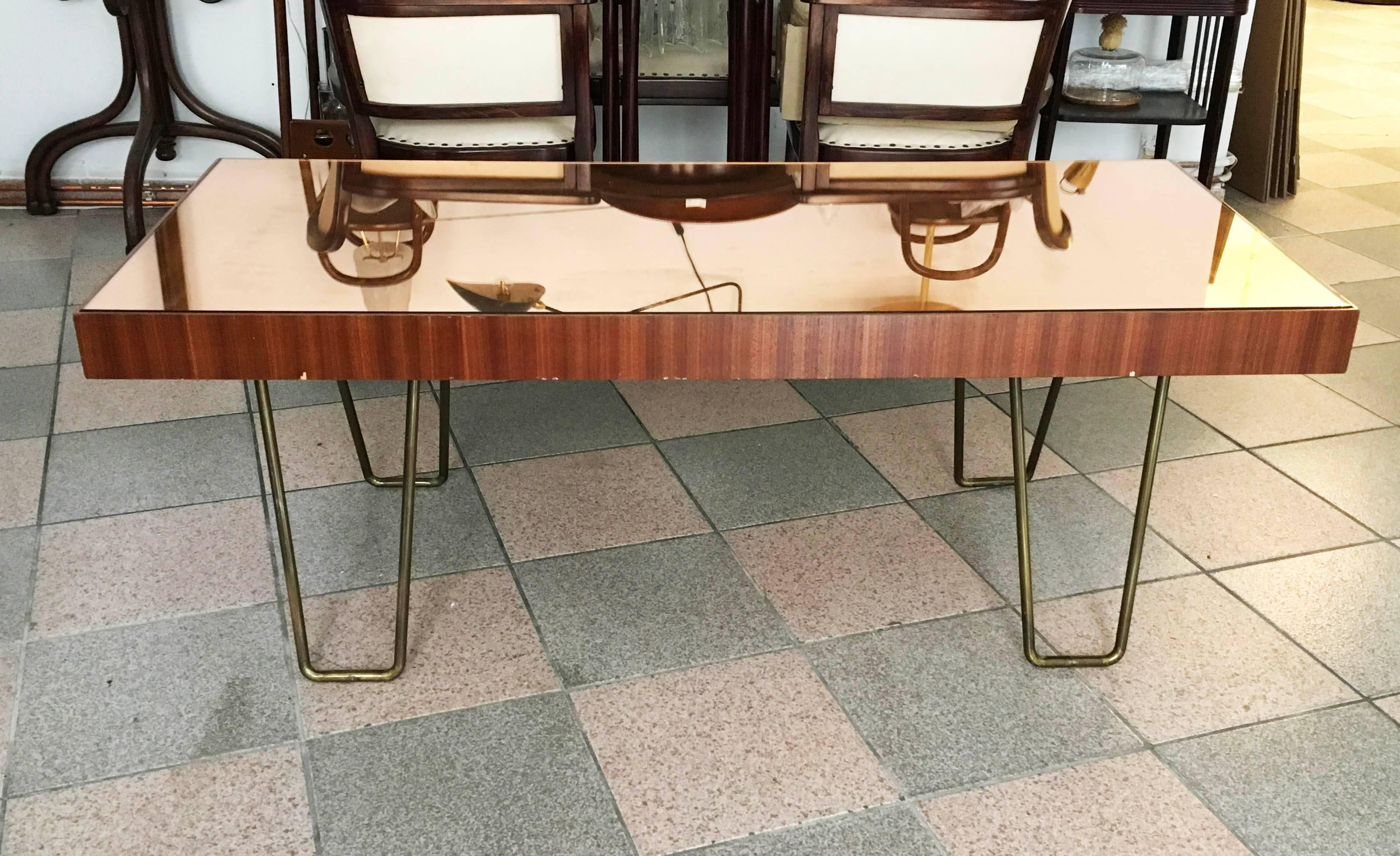 Heavy solid wood construction on brass legs with copper color mirror on the top of the table. Made in Austria in the late 1960s.
Minimal use on wood and glass.
             