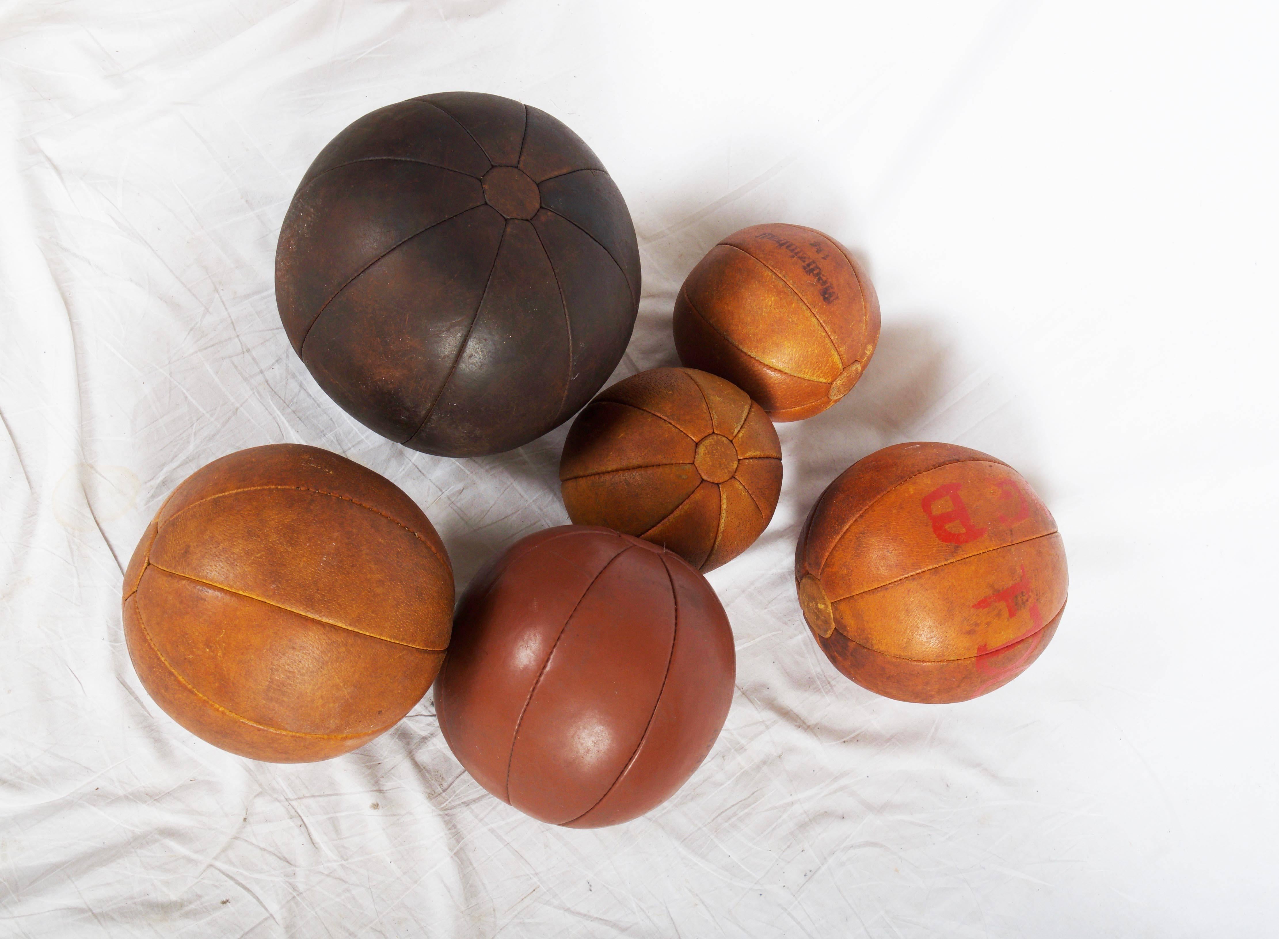 Original patinated leather medicine balls, two with 1kg, two with 2kg one with 1.5kg and one with 3kg diameter from 20 to 35cm, made in Germany in the 1950s.