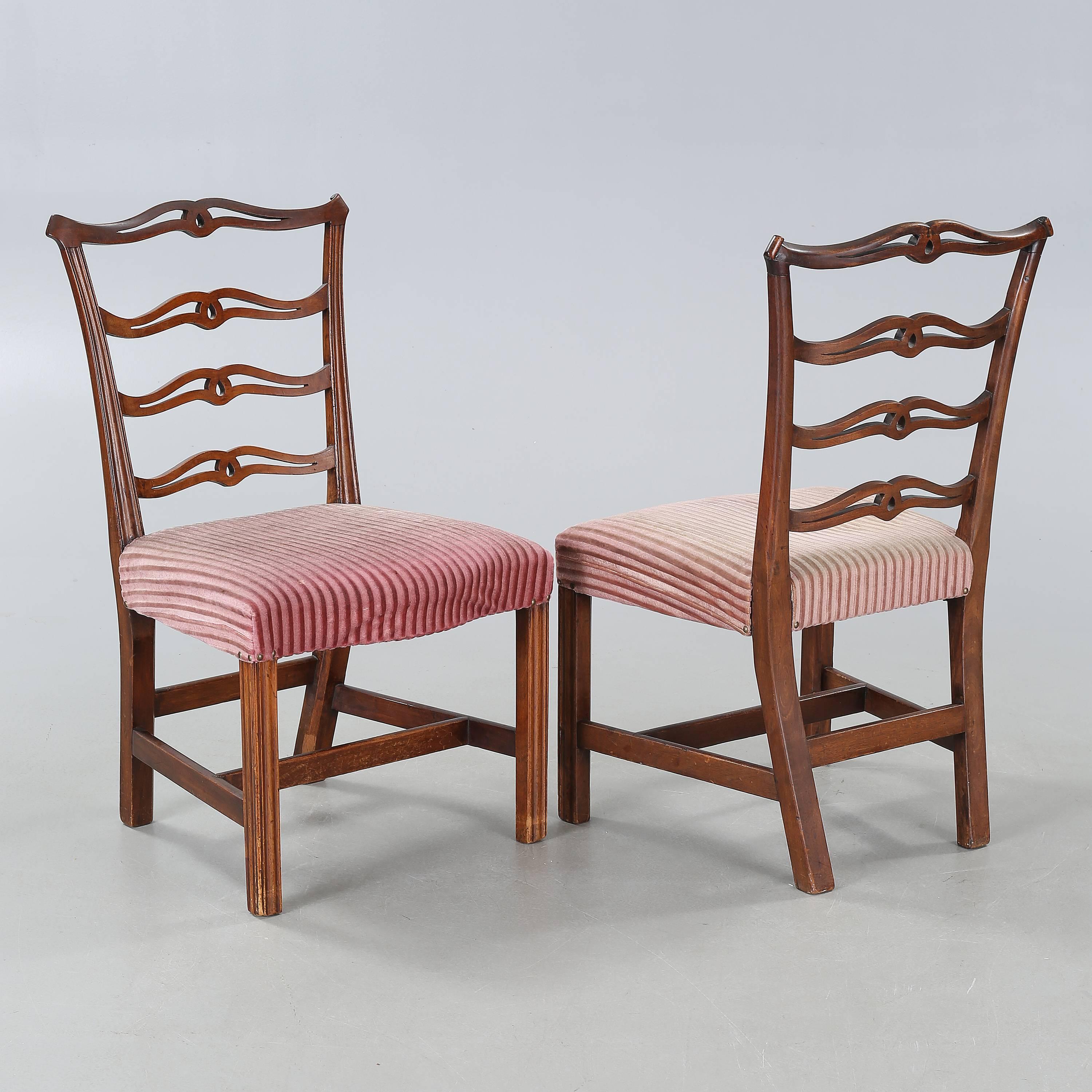 Solid mahogany chairs. The shaped crest with carved ears above four undulating pierced splats over a molded trapezoidal slip seat raised on straight molded legs joined by an H-stretcher. Made in the United Kingdom in the 1950s. Will be sold 