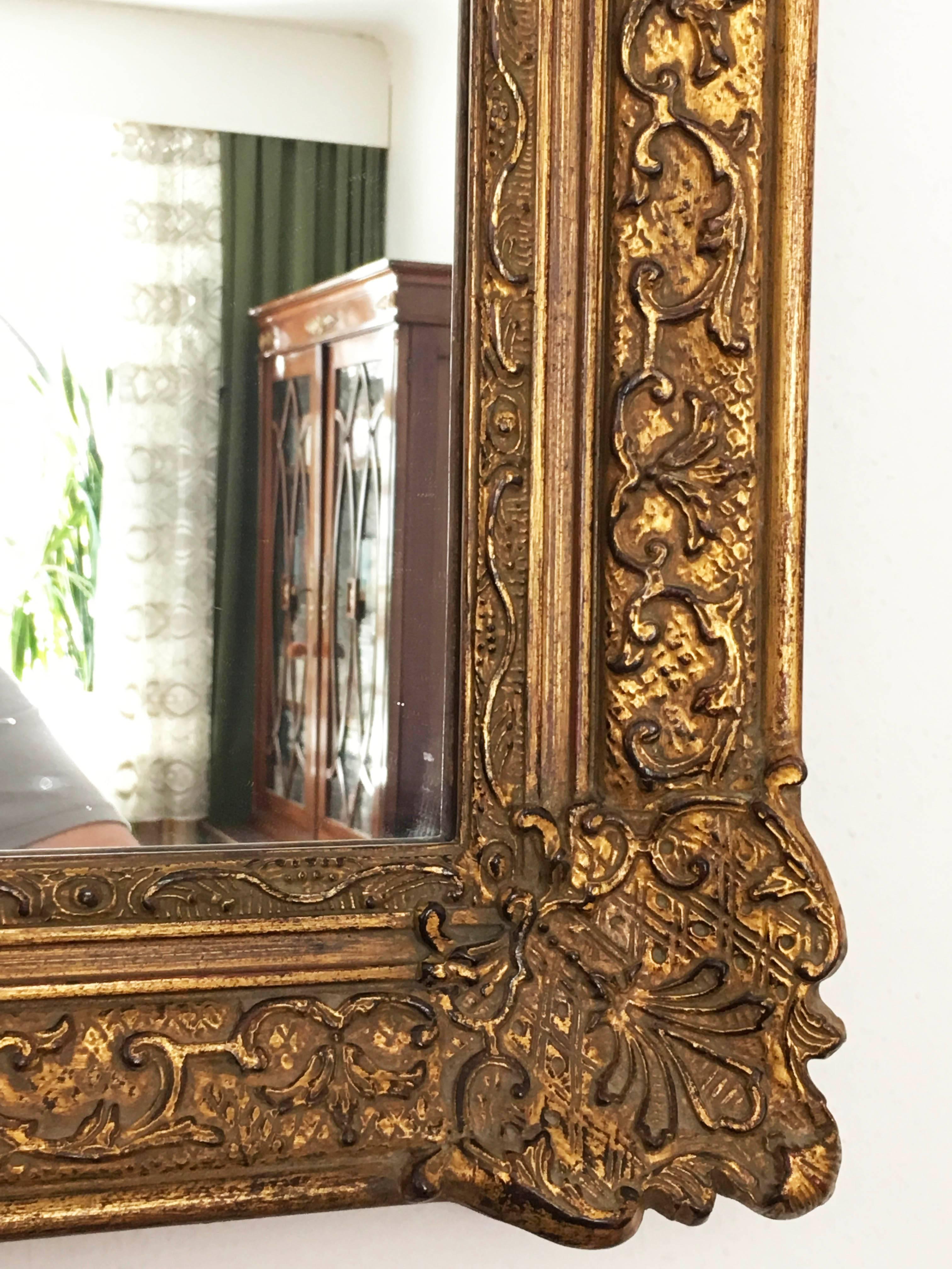Made in early 20th in Baroque style giltwood carved mirror, the shaped frame carved with floral motifs, leaves, flowers. Water gilding of polished and matte quality, with some bleeding of the bole, the mirror plate recent replacement.