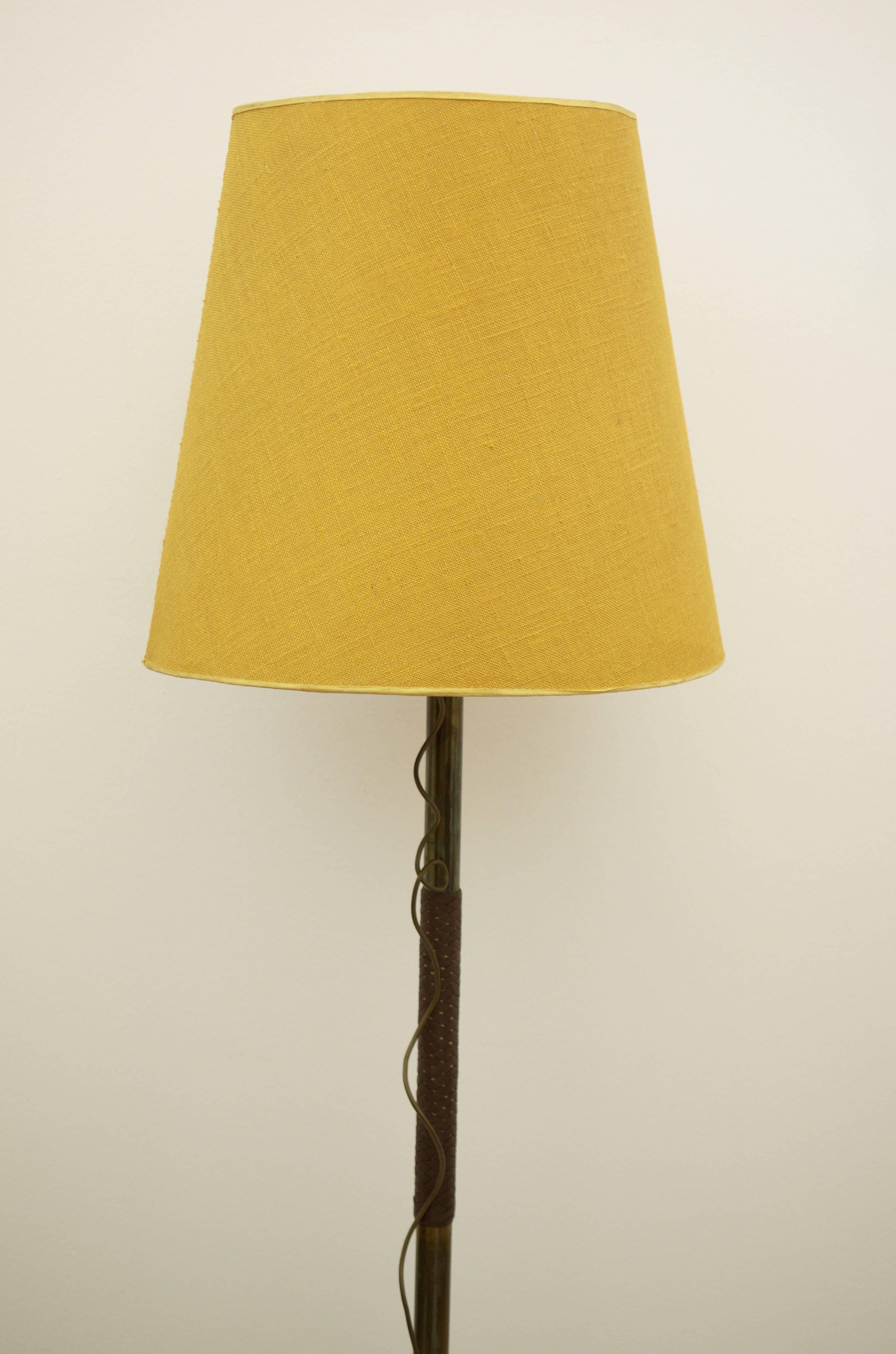 Lampe aus Messing mit zwei E27-Glühbirnen und Schalter mit langem Kabel.
In der Mitte des Lampenbeins aus Messing ist ein Teil des Beins mit Leder umflochten.
Lampenschirm aus Leinen, wahrscheinlich von J.T. Kalmar in den 1940er oder frühen 1950er