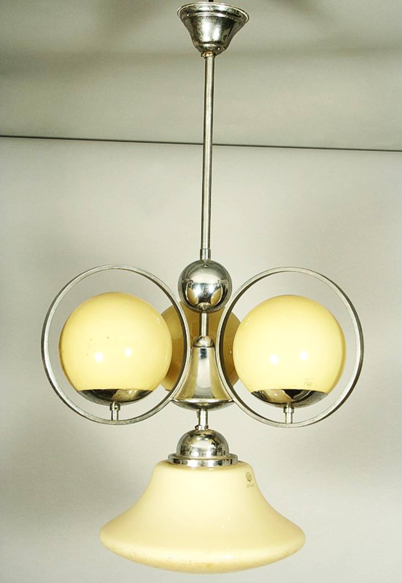Lustre Art Déco en laiton chromé avec trois abat-jour sphériques et un abat-jour en forme de cloche en verre bicouche intérieur blanc extérieur beige des années 1930.
Il faut refaire le câblage !