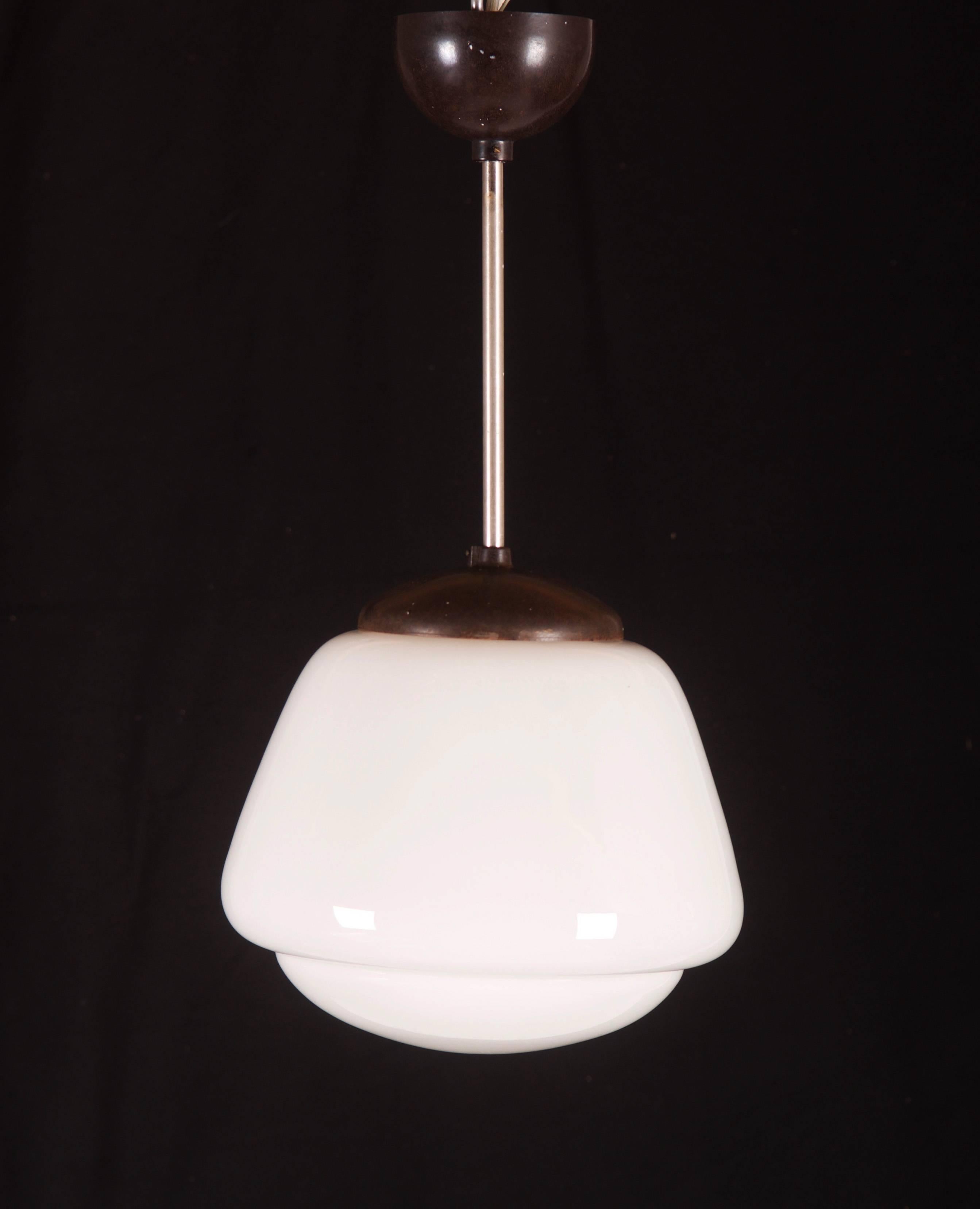 Bauhaus pendant from the 1940s.
Opaline glass shade mounted on a steel construction, cover and shade made of bakelite.
Up to 20 pieces available.
