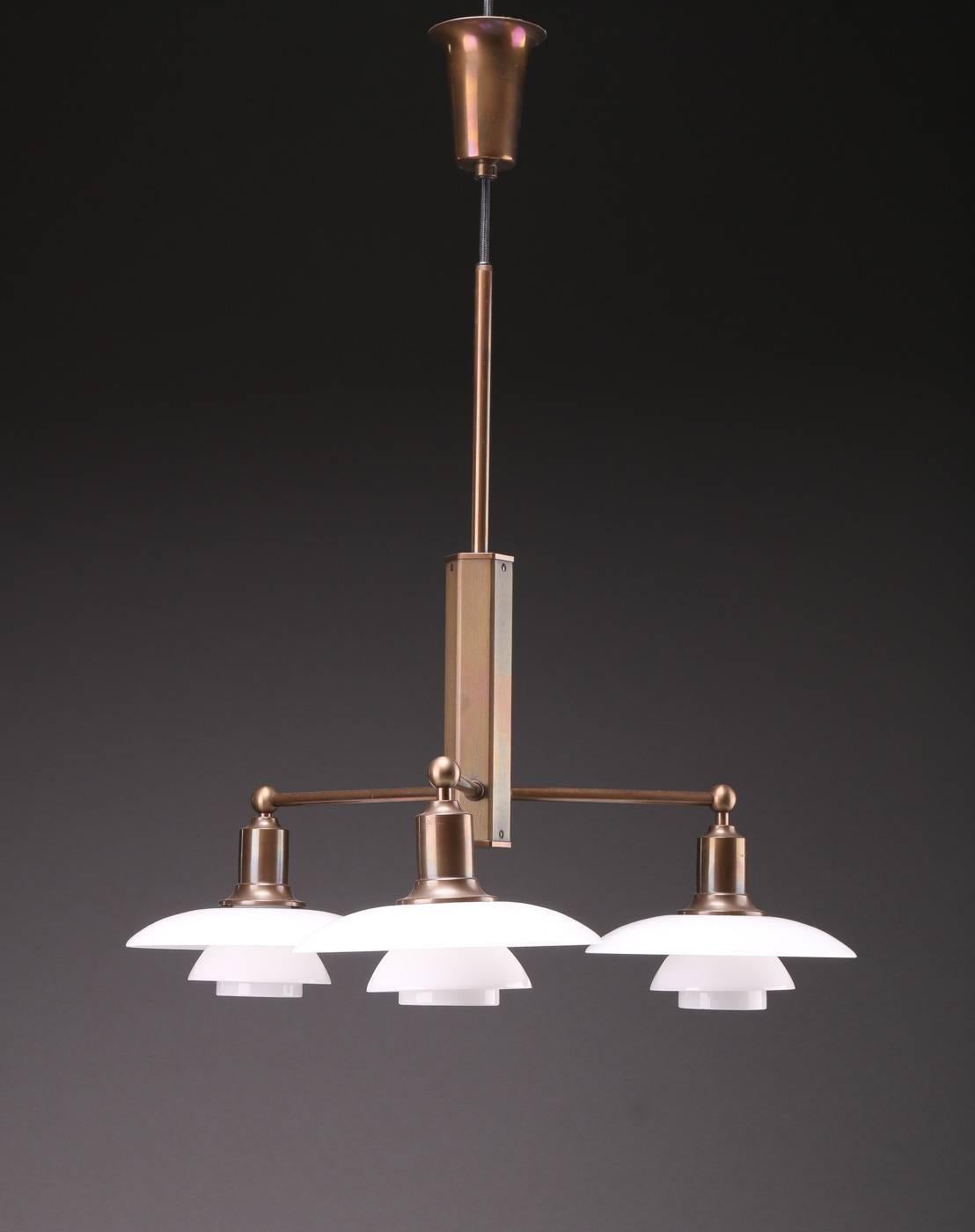Poul Henningsen 1894-1967. PH stem fitting, browned brass, three branches with 2/1 shade in white opal glass. Produced by Louis Poulsen for a limited time and is no longer in production. Traces of marks on one arm.