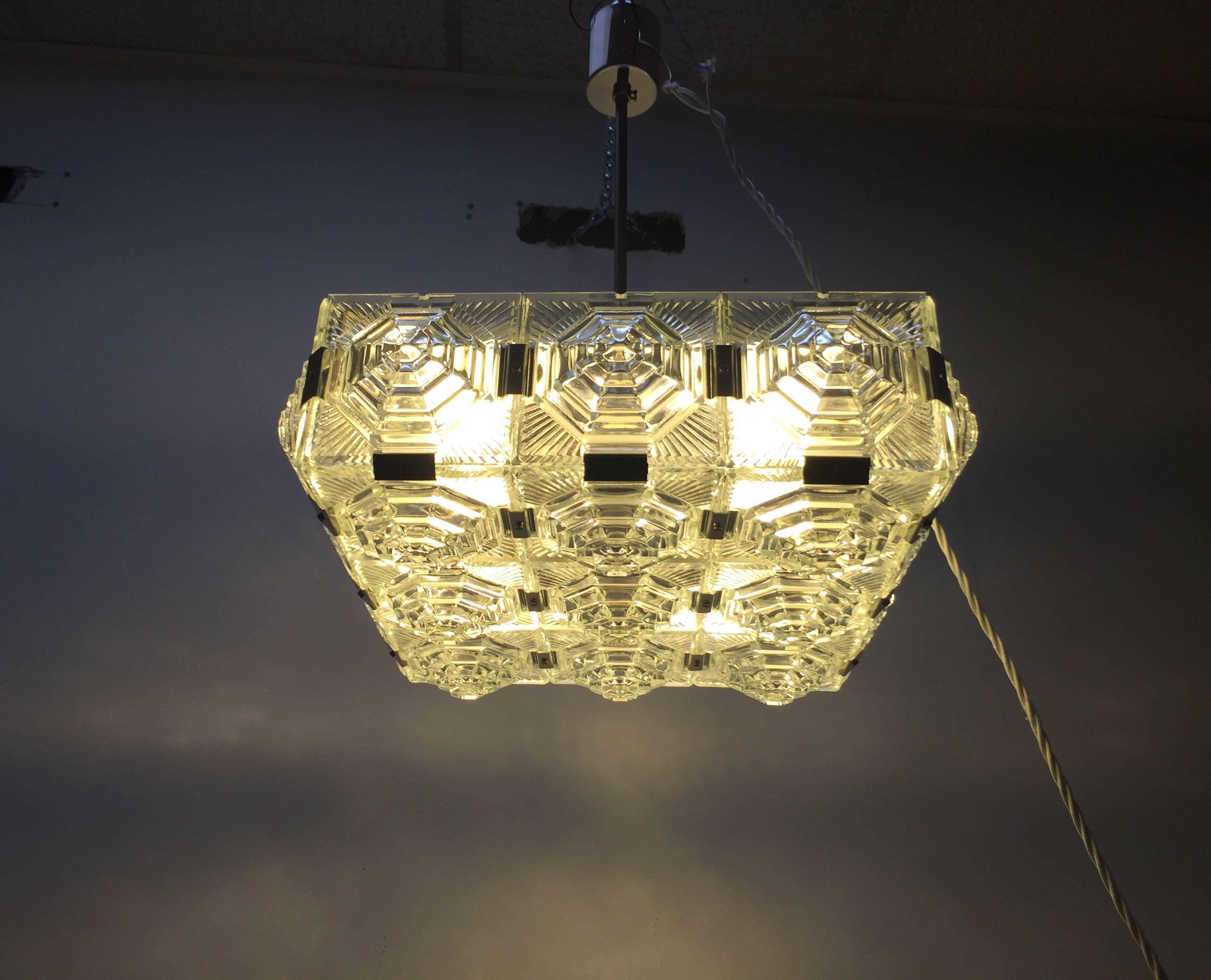 Mid-Century chandelier in the style Kalmar.
It consists of 21 squares each glass with an intricate sunburst design that has been hand etched into the glass.
Each square is individually attached to the next with nickel fittings giving the