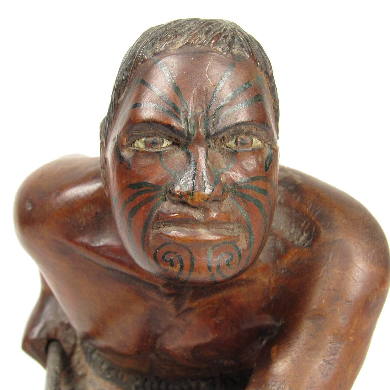 Early 20th century carved and polychromed figure of a kneeling Maori warrior with fierce expression and face tattoo, holding a spear in a defensive posture. Unsigned, Dimensions: 8 x 6 x 4 inches.