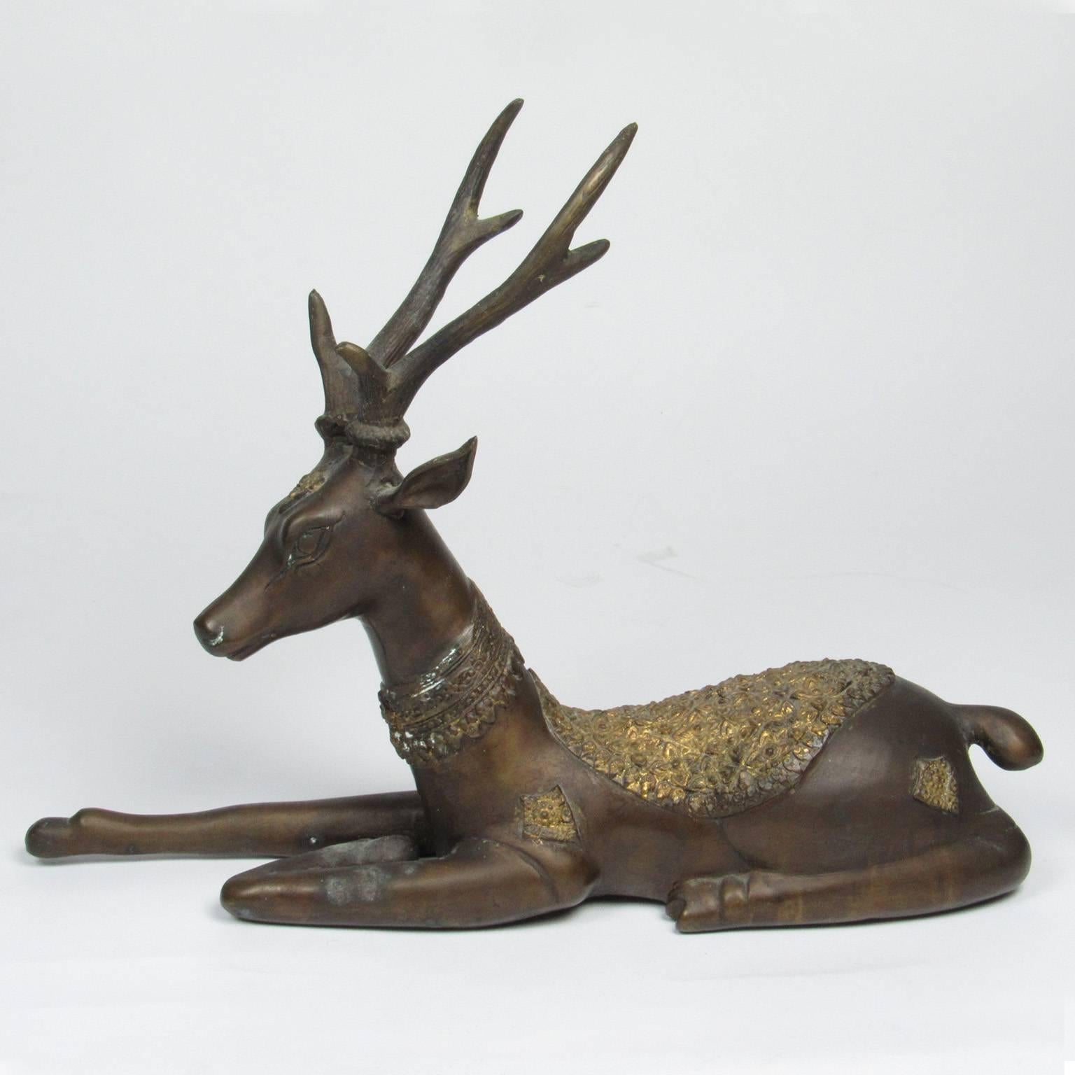 Pair of Southeast Asian bronze reclining deer, late 19th-early 20th century. Each with brown patina with decorative saddles and collars with gilt wash. Measures: Height 9 in., length: 12 in., width: 4 in.
