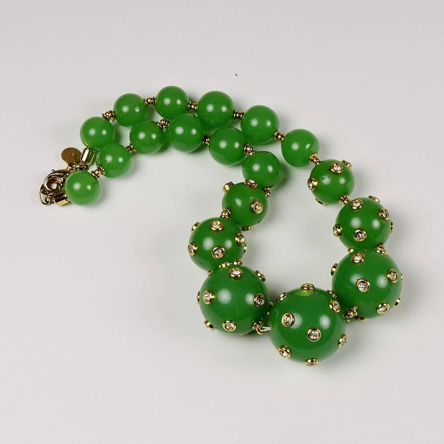 This festive vintage Valentino Garavani graduated green bead necklace is encrusted with crystal studs set in yellow gold tone mounts. A small pendant marked 
