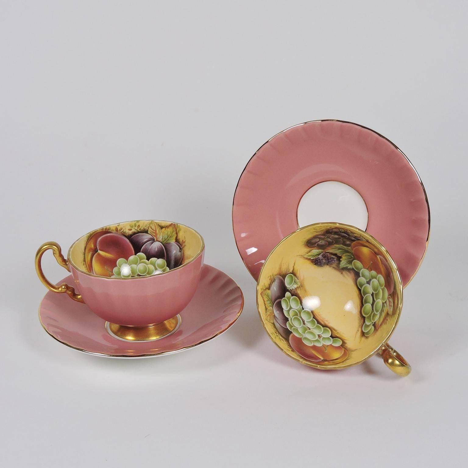 Set of Twelve English Aynsley Bone China Cups and Saucers.  Pink ground exterior with gilt handles, decorated with peaches and grapes on yellow ground on interior.  Diameter of saucers: 5 1/2 inches; height of cup: 2 1/4 inches