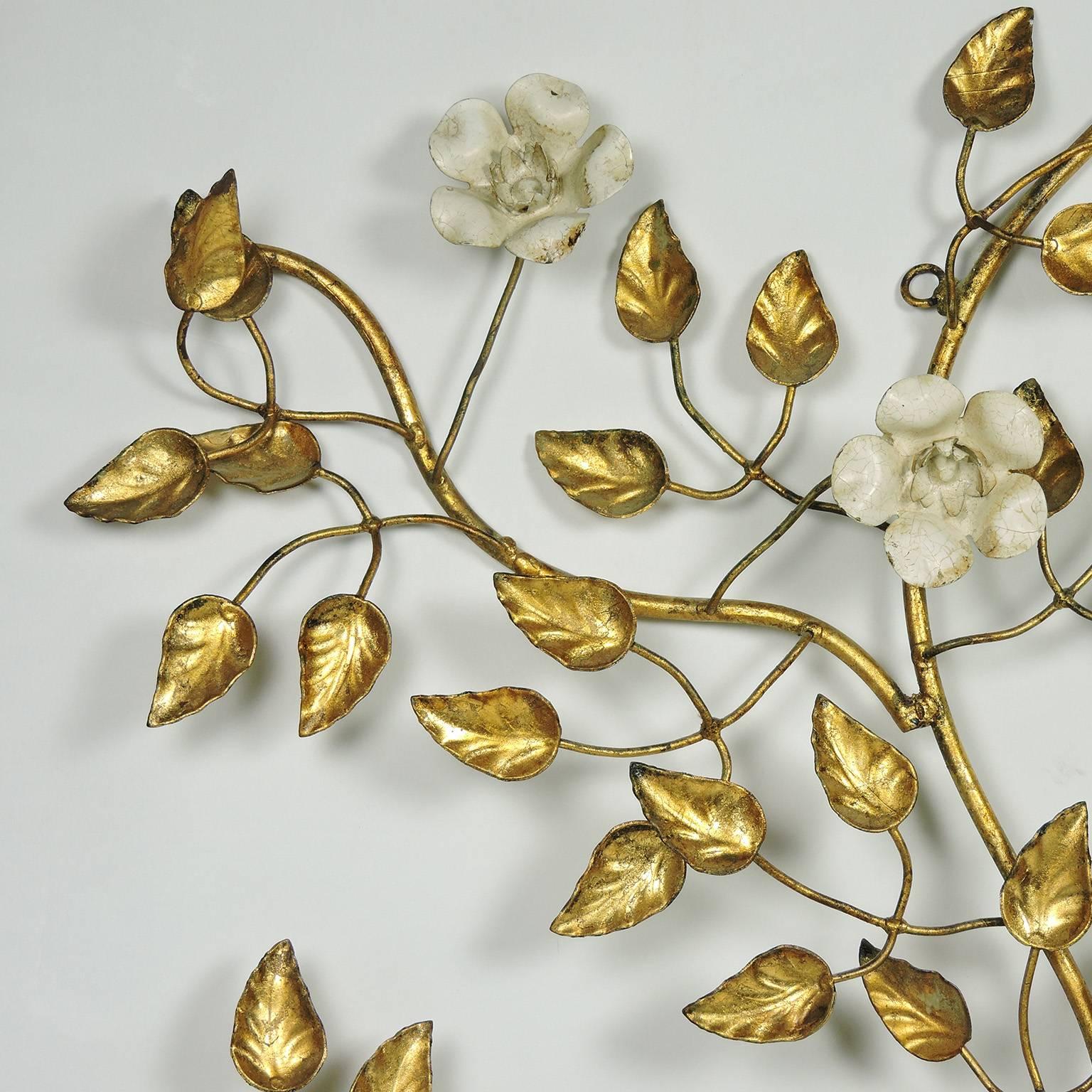 Vintage Italian Mid-Century Modern gilt and tole painted metal floral wall decoration, 20th century. Comprised of a meandering vine of gilt branches and leaves adorned with white tole flowers. 