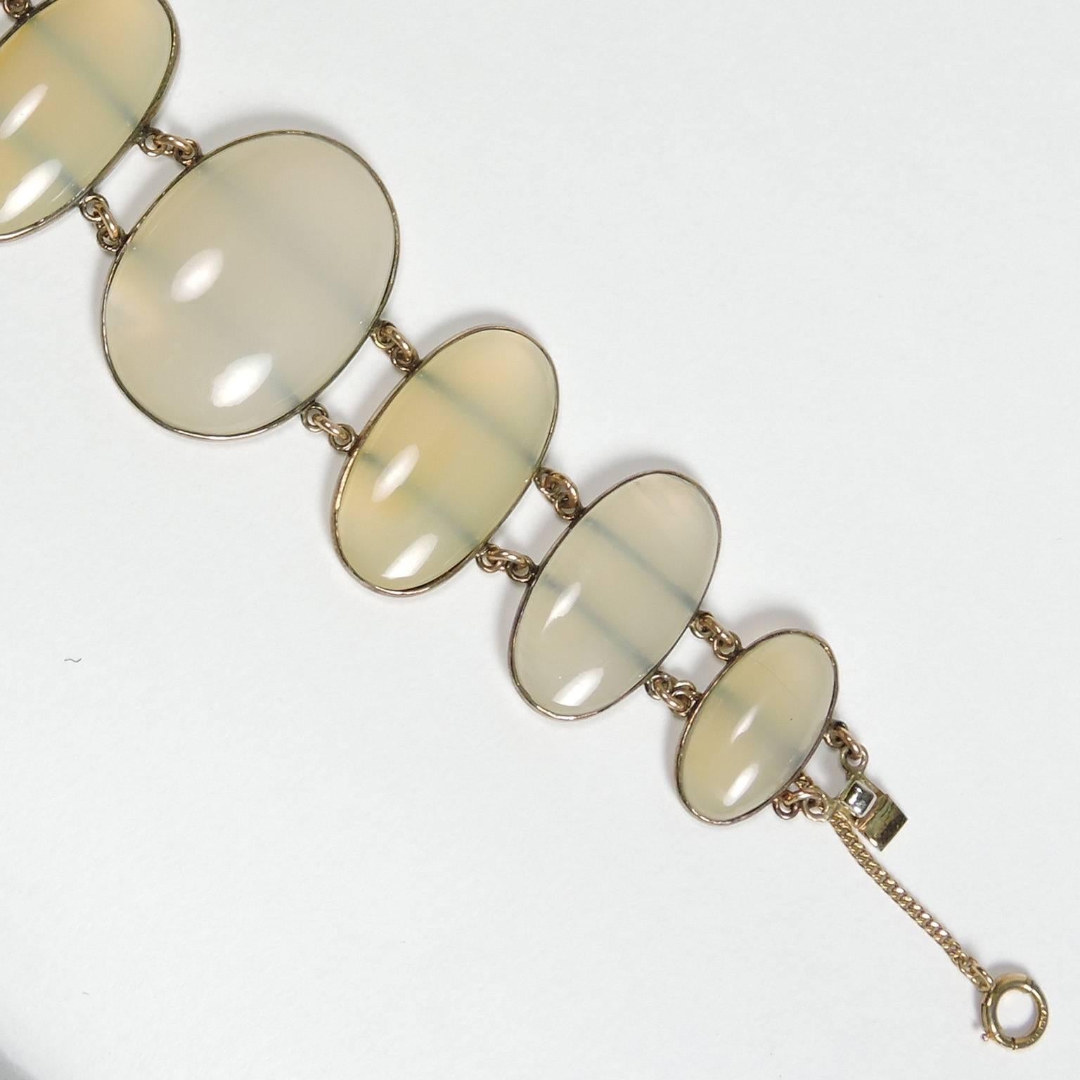 Vintage graduated transluscent white Cabochon Agate and yellow gold bracelet.  Comprised of eight graduated oval Cabochons with varying degrees of yellow set in a gold. Length: 6 inches, graduating from 3/4 to 1 1/4 inches