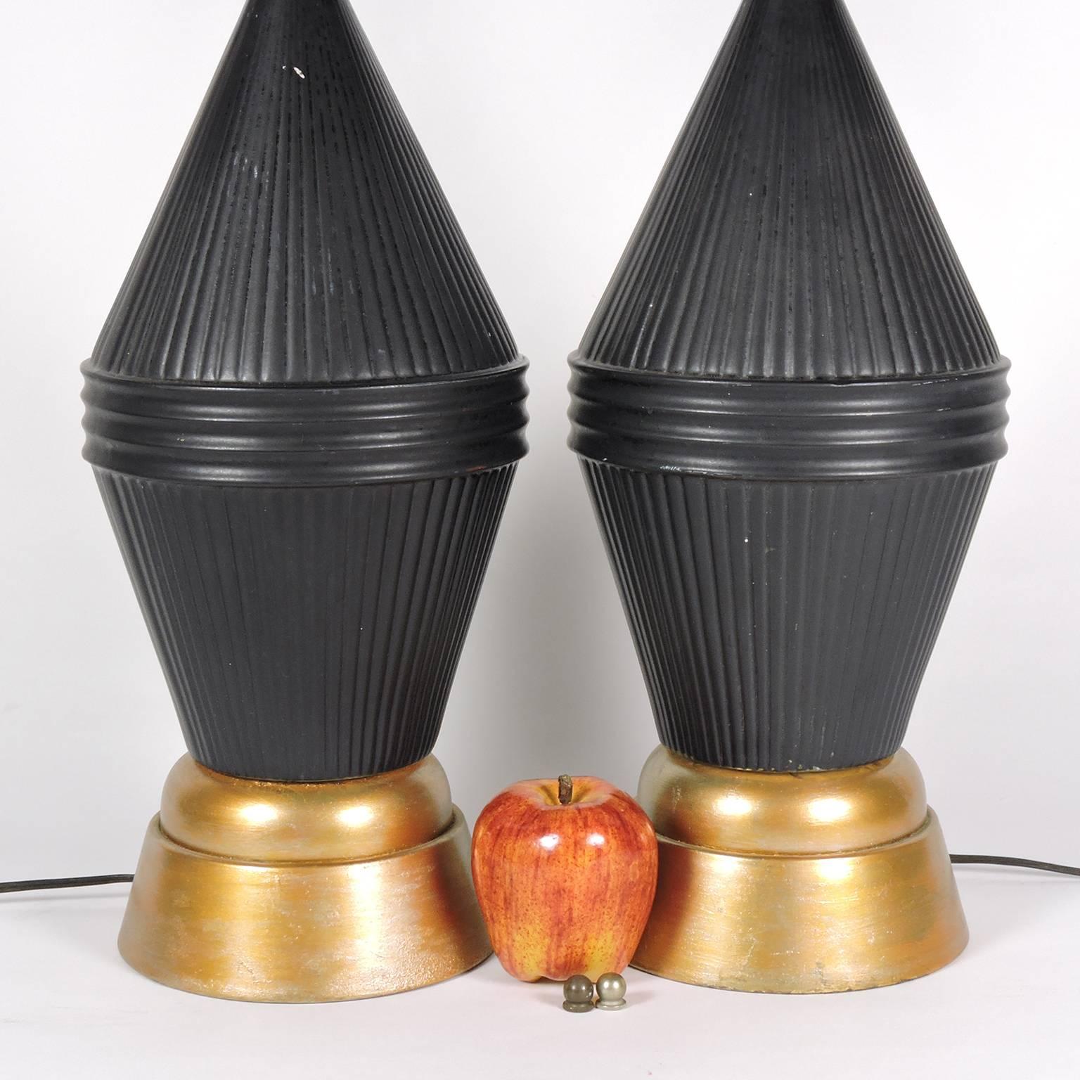 Pair of Mid-Century Modern black and gold patinated metal table lamps, 20th century; with complimentary black shades. 
Measure: Height 27 inches; diameter of shades 15 inches.