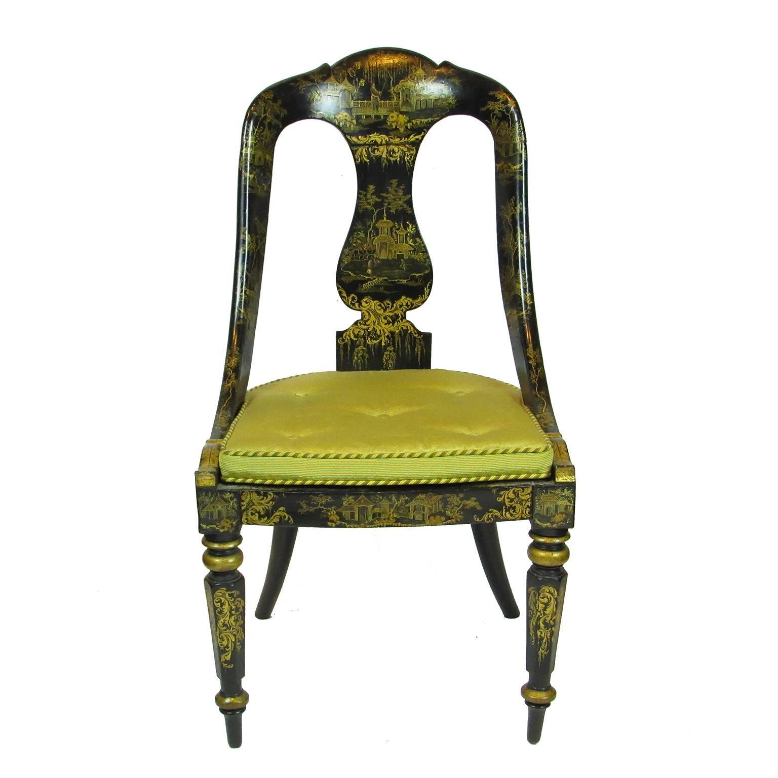 Antique 19th century pair of Japanned and chinoisserie gilt decorated cane seat chairs, japanned in black with gilt chinoisserie decoration, gold seat cushions, shaped central back splat, turned legs ending in arrow feet; Overall height: 37 inches;