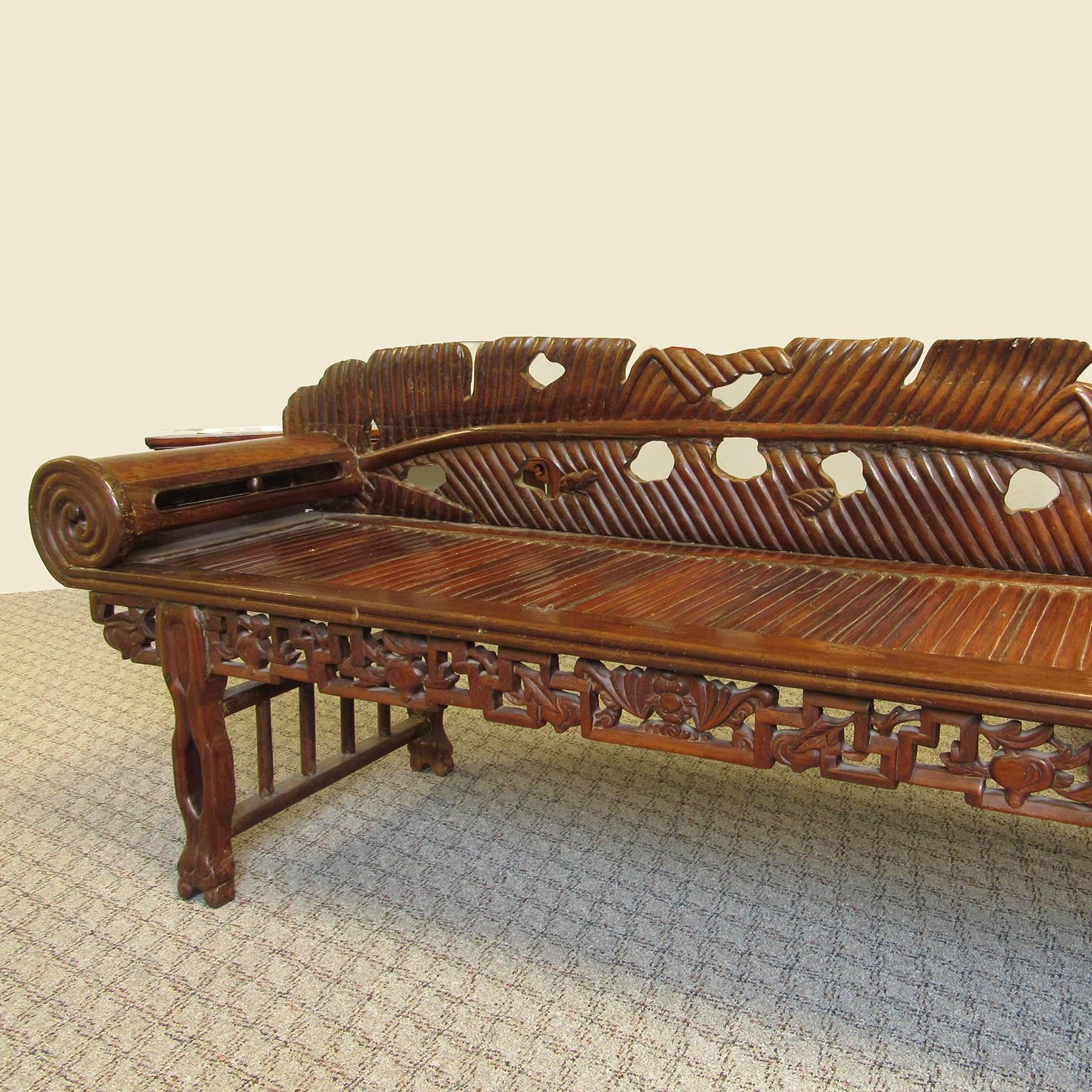 Antique Asian carved hardwood scroll arm chaise, late 19th to early 20th century. With palm frond back, and oranate pierced fretwork rased on twisting vine legs.
Overall height: 29 1/2 inches, seat height: 17 3/4 inches, length: 69 inches, depth: