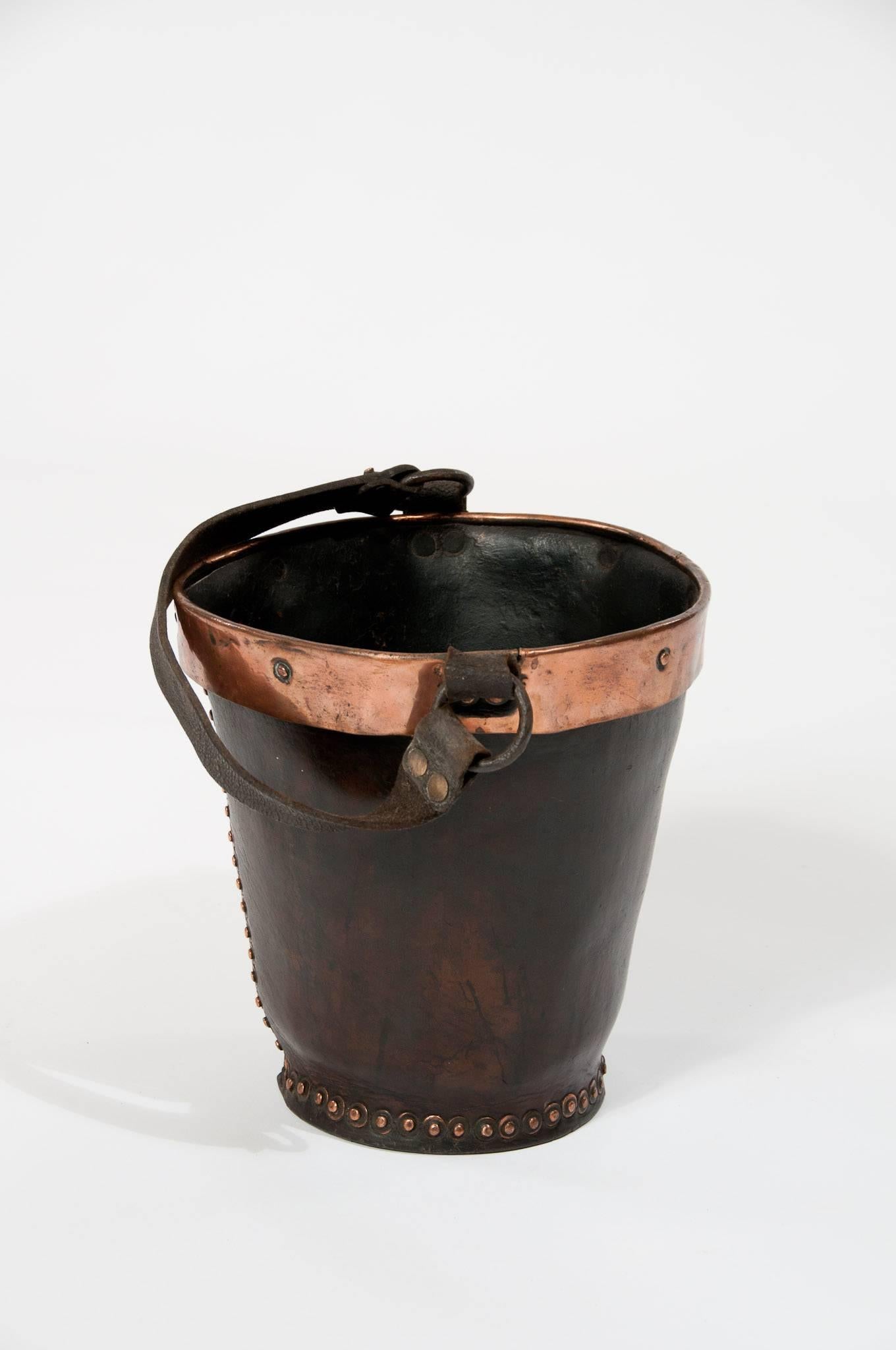 A good example of a mid-19th century antique leather fire bucket. In good condition with a lovely original waxed color. 
Retaining its original leather carrying handle with the top being edged in copper having rivets down the seam and around the