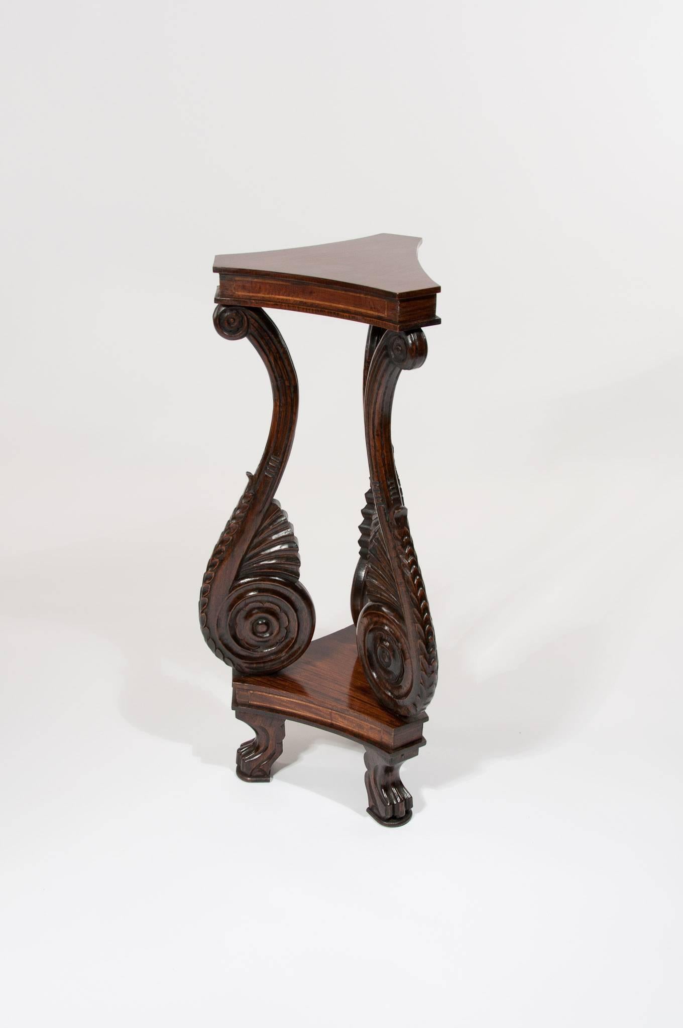 A very well carved solid rosewood shaped stand. Having a shaped top with inlaid frieze supported by three shaped scrolls of shell form raised on carved cabriole claw feet.
Of very good color and well made in solid rosewood this unusual stand dating