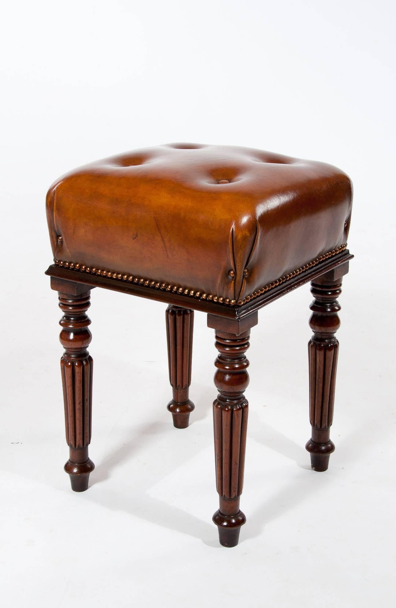A very fine quality Regency/William IV mahogany reeded leg leather upholstered stool. The top is upholstered in a quality leather hide which has been hand dyed in the traditional manner and shallow buttoned with a brass nailed studded finish.