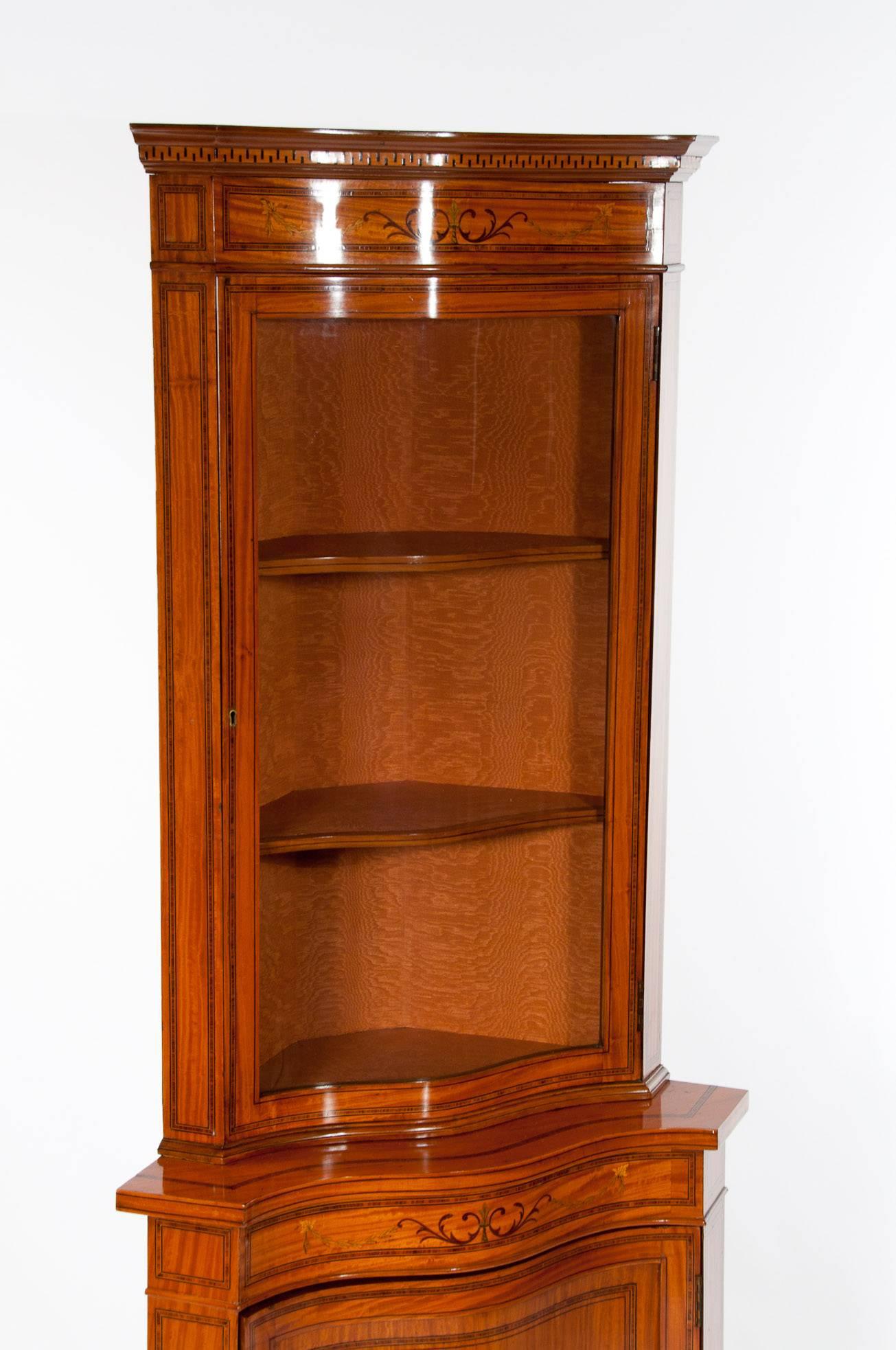 A very fine quality Inlaid Edwardian satinwood serpentine shaped corner cabinet. 
This quality Satinwood corner cabinet has been extremely well made dating to circa 1905. 
Having a dentil moulded cornice with marquetry inlaid frieze above a