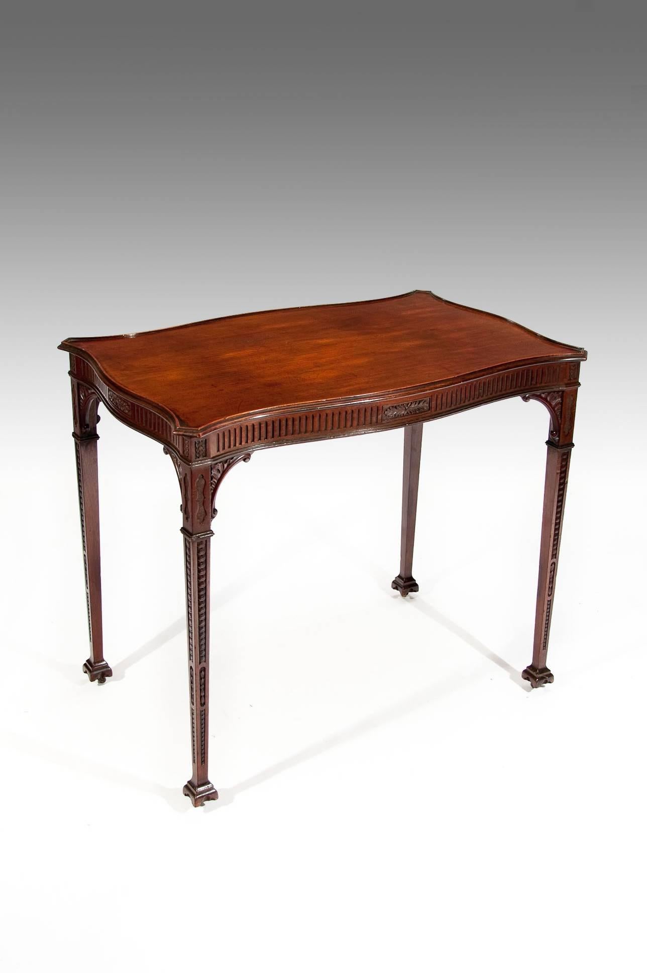 A very elegant 19th century antique mahogany serpentine silver table on carved and tapering legs. Having a superb quality serpentine shaped solid mahogany top with lipped and moulded edge over a fluted and carved frieze having central carved rosette