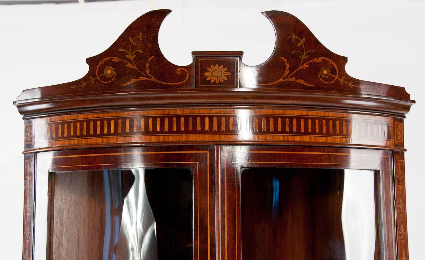A very fine inlaid bow fronted mahogany two door corner cabinet with marquetry in the manner of Edwards and Roberts. This antique mahogany corner cabinet is has been made to the finely quality dating to 1890. Profusely inlaid with garlands, swags,