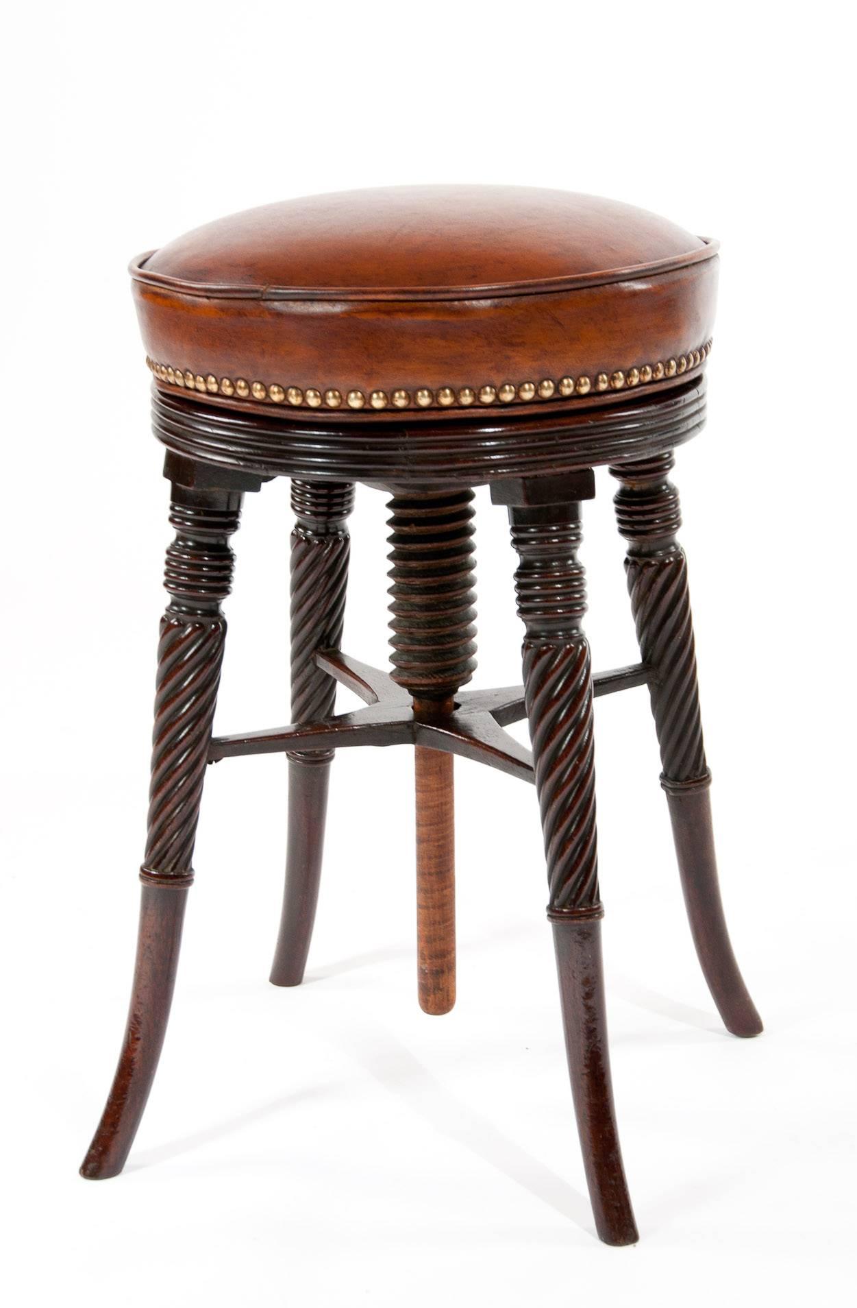 A fine quality Regency adjustable piano stool with a leather upholstered seat. The round tan leather seat being fully adjustable by simply turning to the required height which is support by four of the most elegant turned and twist reeded legs