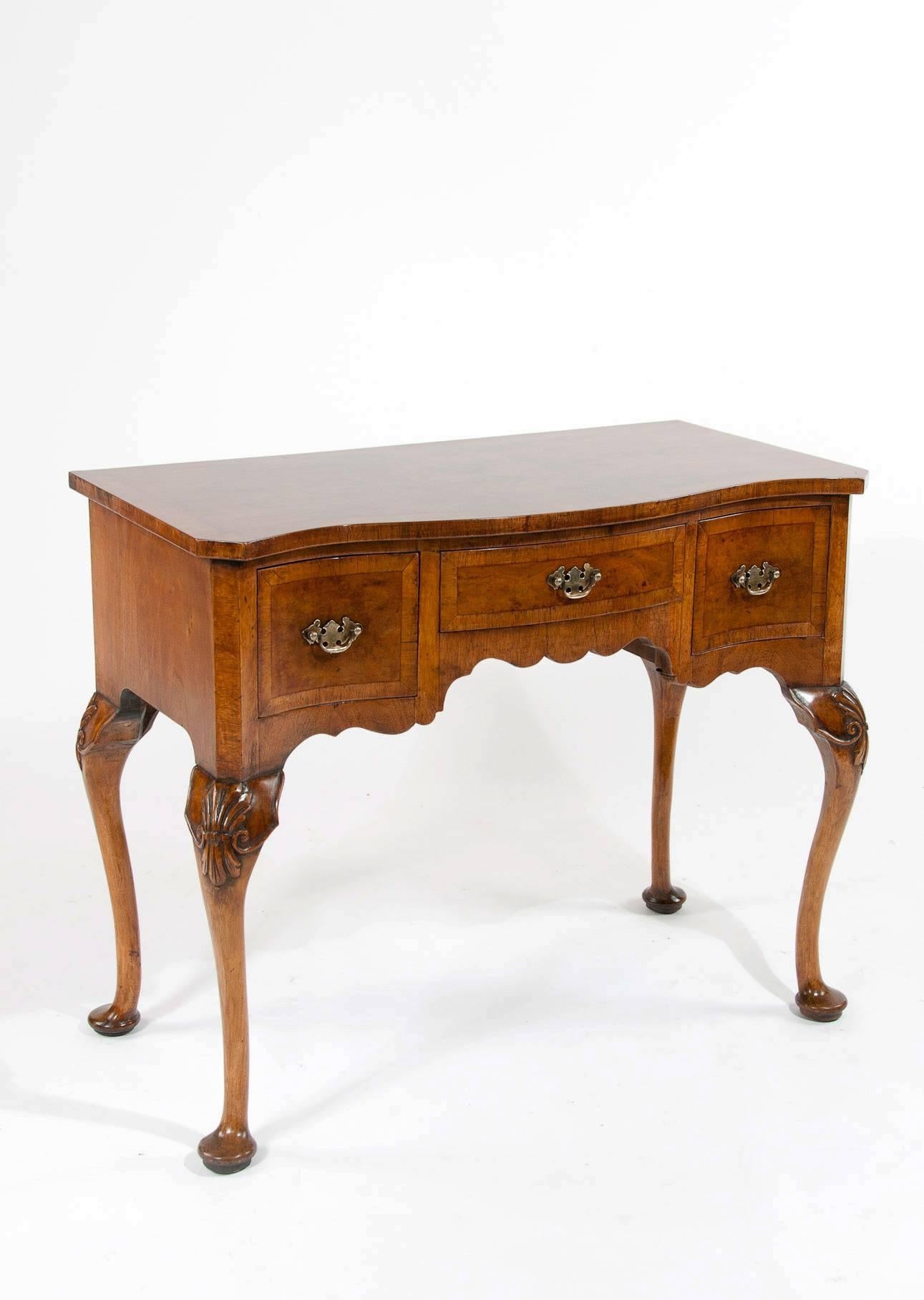 A very good quality antique burr walnut serpentine shaped lowboy stand on cabriole legs. This lovely quality lowboy constructed from fine walnut veneers has a serpentine shaped top being quarter veneered in figured walnut with a crossbanded edge