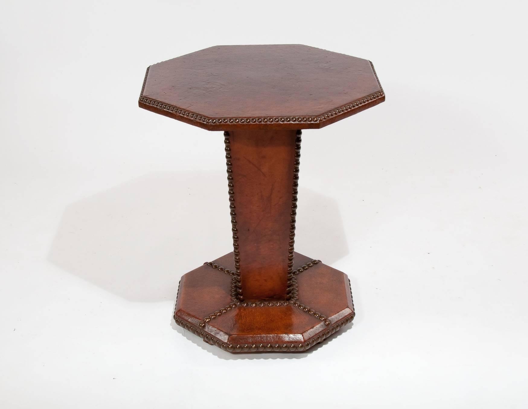 A quality French leather hexagonal side table with brass nailed finish. This quality Art deco side table dating to the 1930s has been completely covered in a tan leather hide having a hexagonal top with brass nailed edge over a tapering square base.