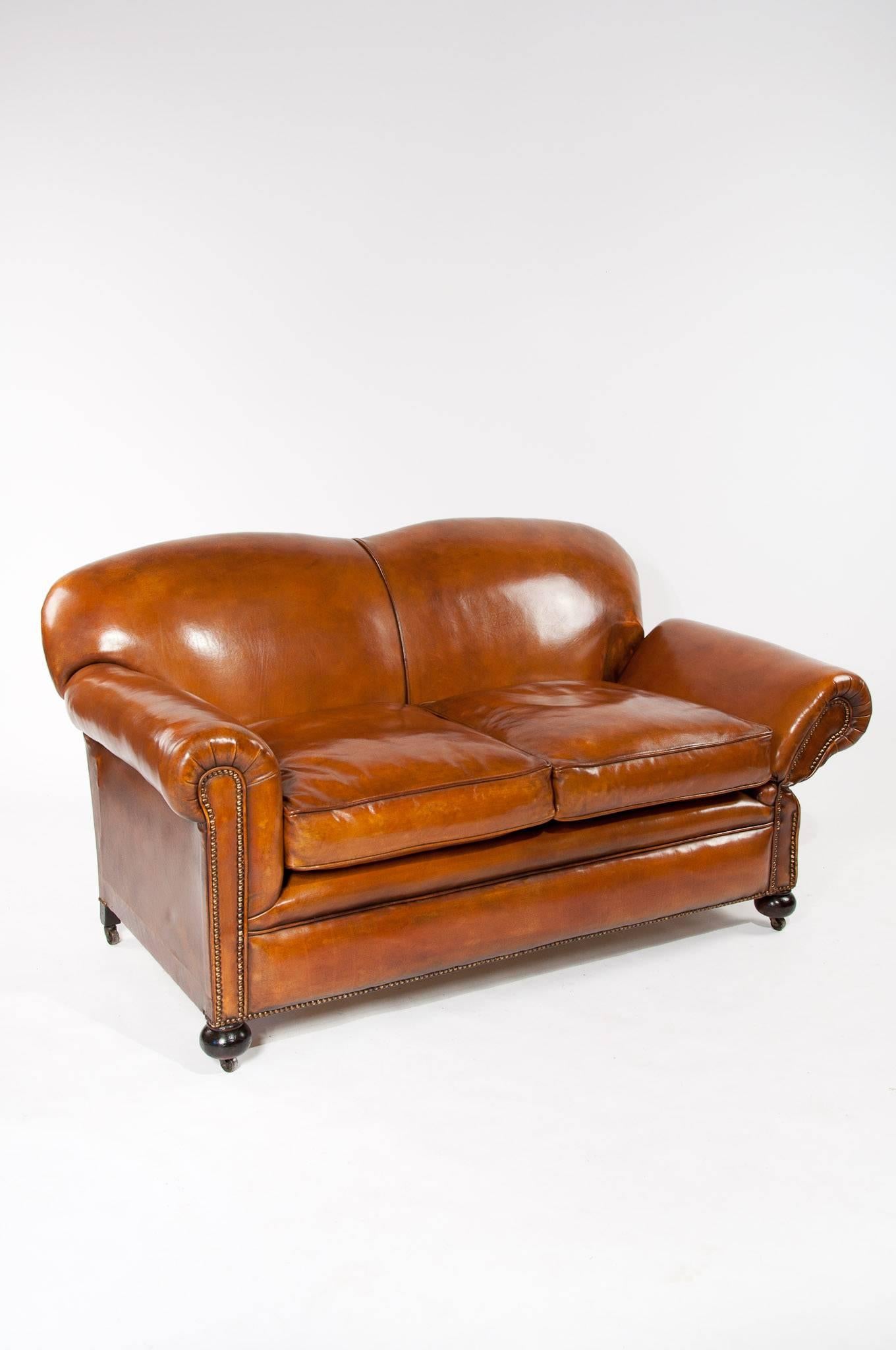 A very good quality Edwardian drop arm leather sofa / couch / settee upholstered in a tan leather.
This well proportioned Edwardian sofa dating to circa 1910 has a shaped back with scrolled arms and a deep feather filled cushion making this sofa