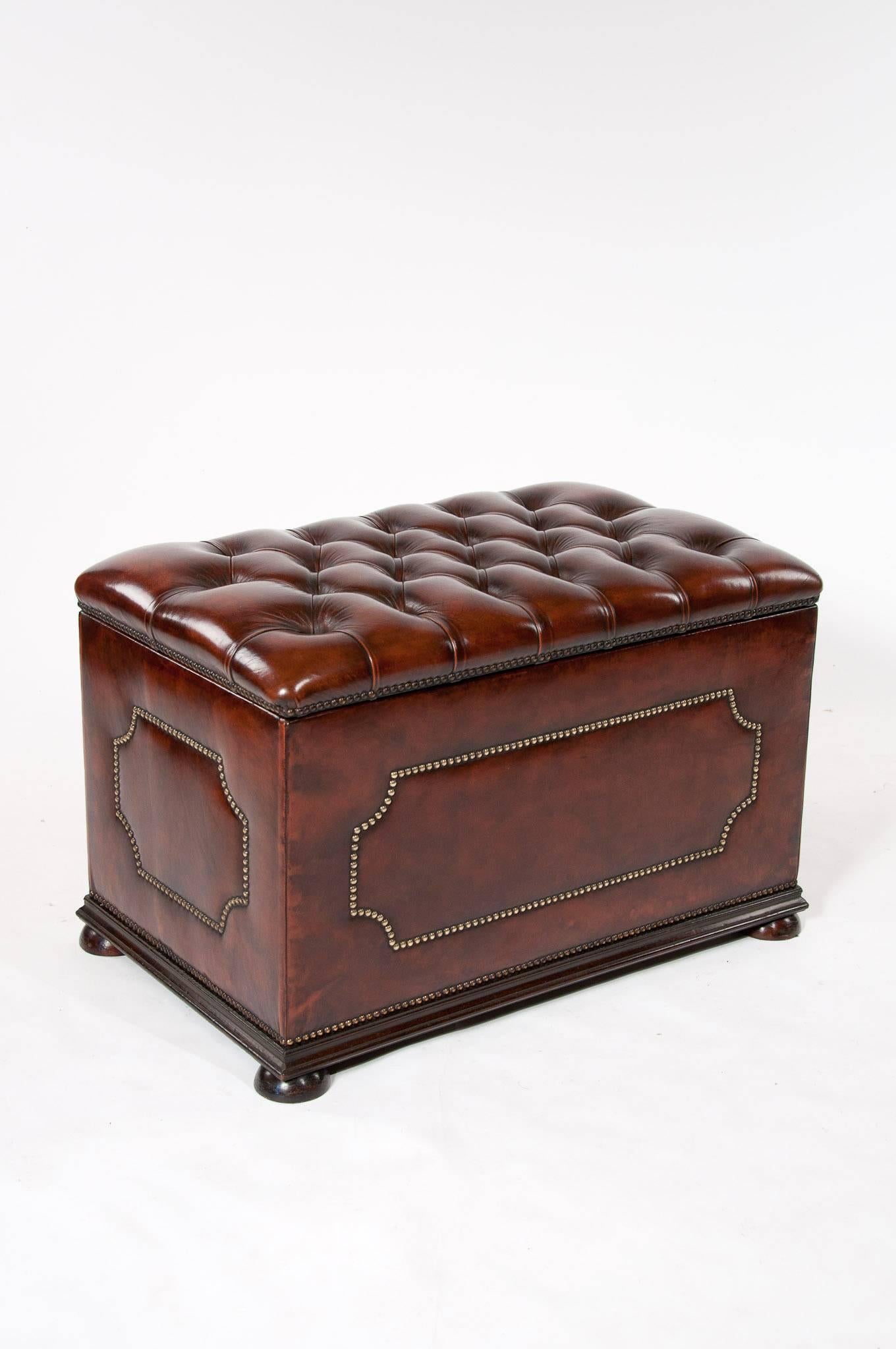 A antique leather upholstered deep buttoned Ottoman with mahogany turned bun feet and decorative brass studding.
 
This ottoman dating to the 1900s has a beautifully deep buttoned leather upholstered lift up top with brass close nail studded edge