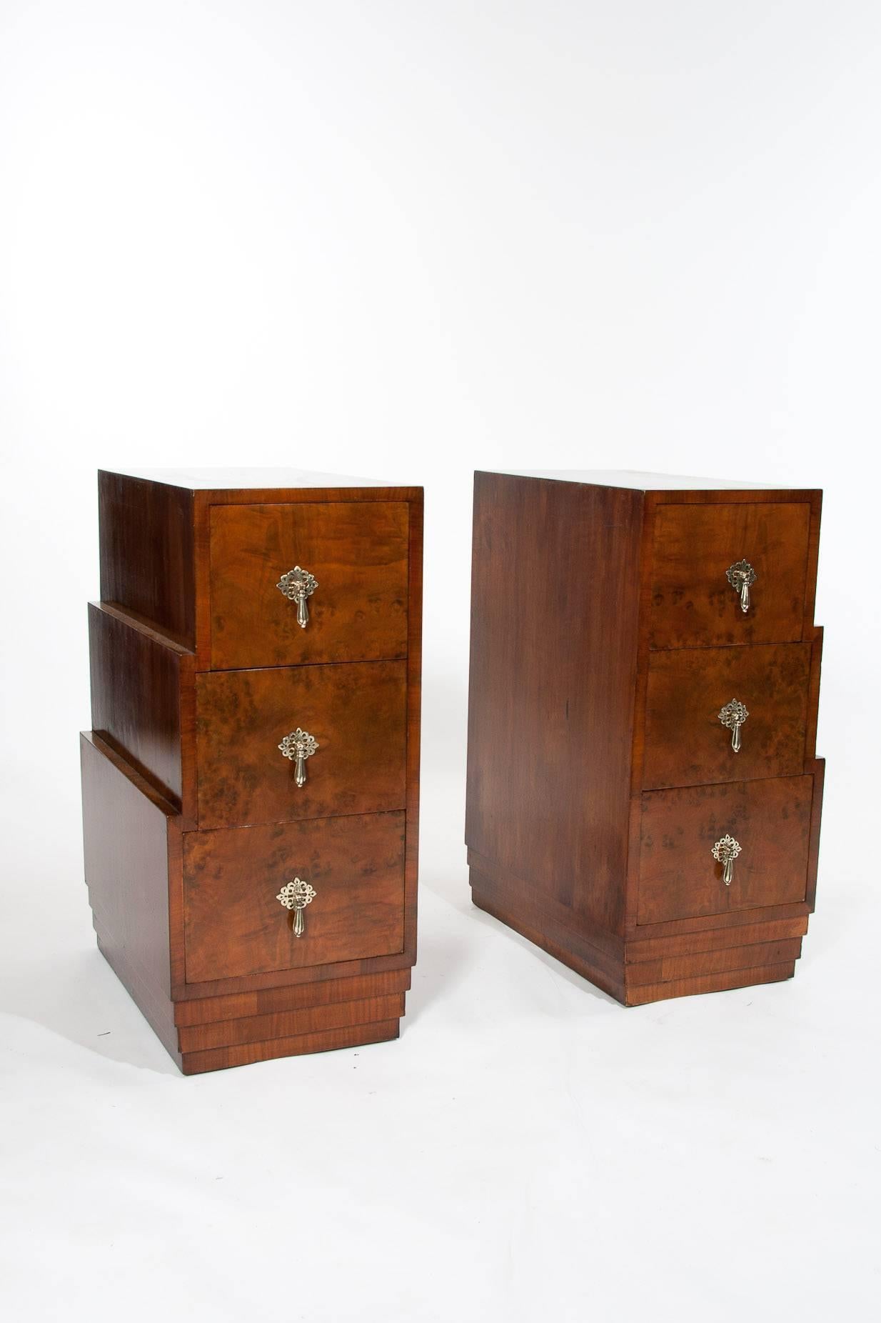 A pair of stepped Art Deco walnut bedside chests or cabinets. 

This quality pair of Art Deco bedside cabinets have a bookmatch veneered walnut top sitting over three stepped drawers graduating in size.

Each drawer having hand-cut dovetails and