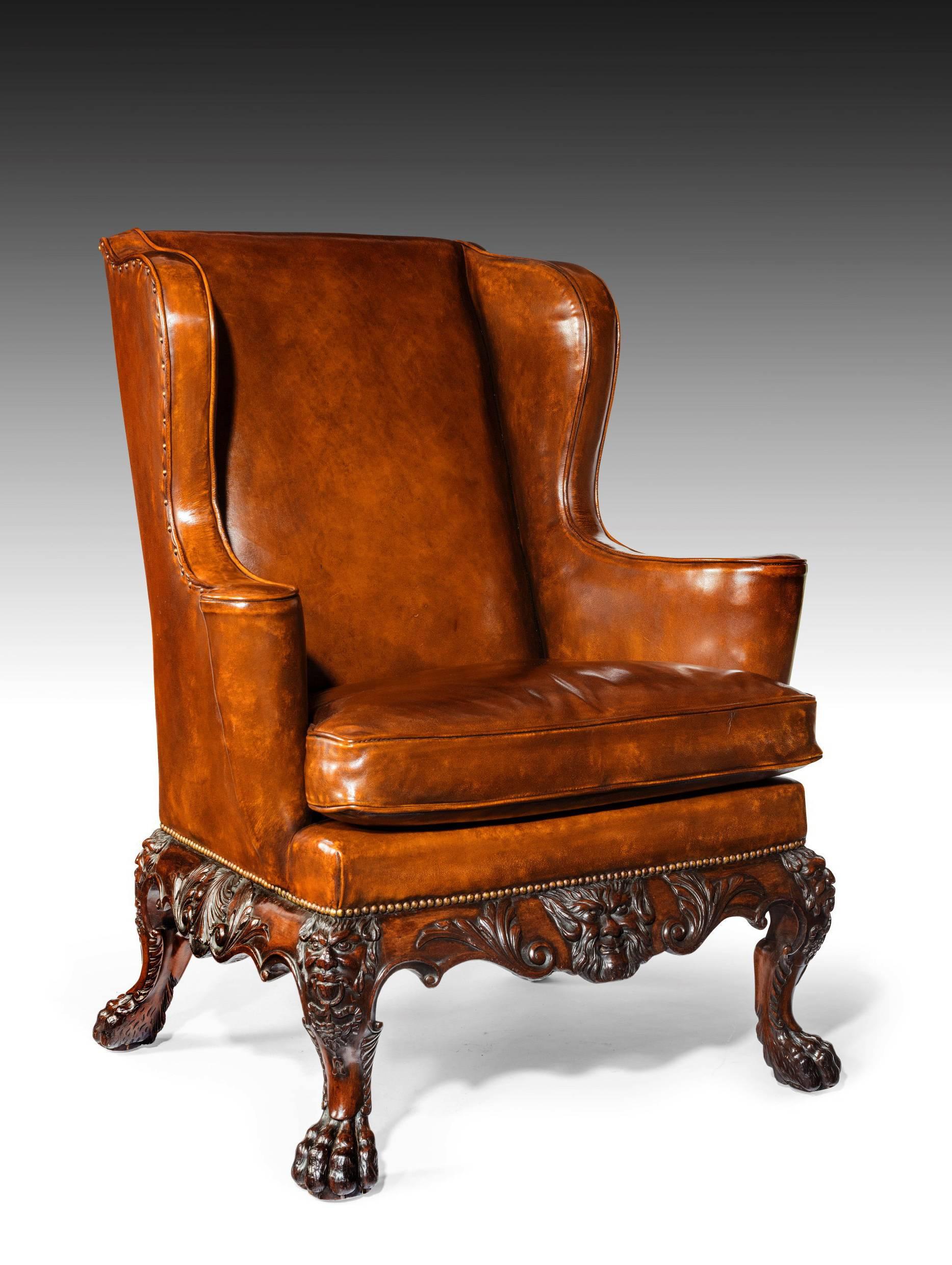 A very handsome and well carved late Victorian leather upholstered mahogany wing back armchair in the manner of Giles Grendey. 
This extremely well drawn chair of imposing size has superb proportions. 
The square back with shaped wings which