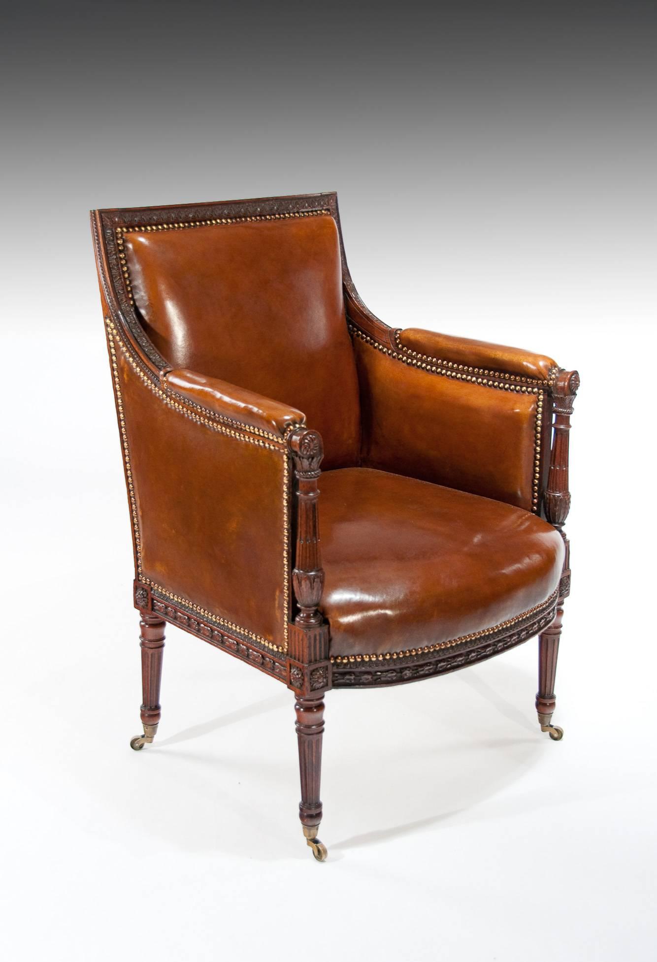 A finely carved antique mahogany and leather upholstered armchair dating to the late 19th century, circa 1880-1900. 

Having a square carved mahogany framed back with padded leather upholstery the arms swept down to a cushioned armrest supported