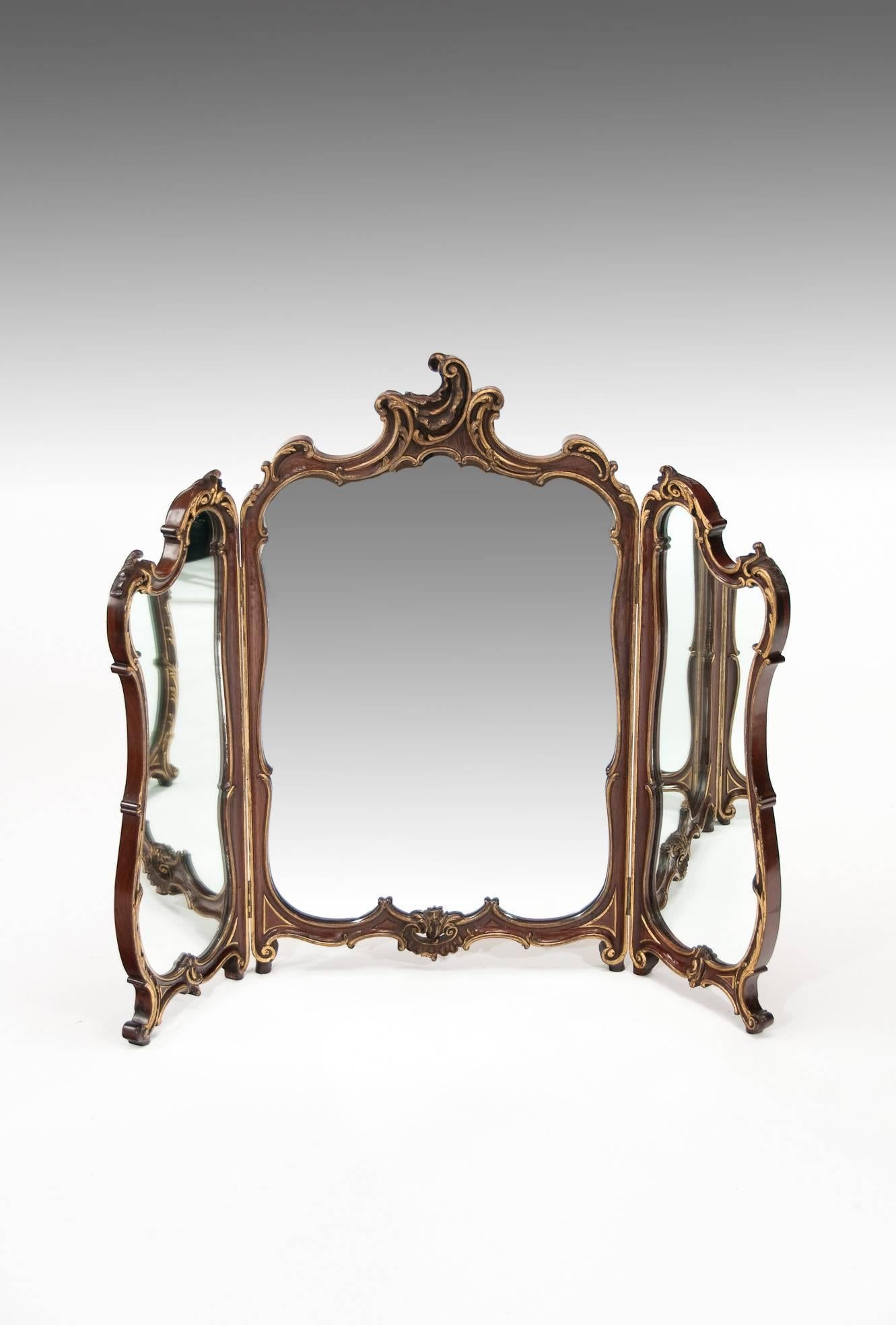 A quality antique mahogany and gilt triptych dressing table mirror. 
This well carved triptych hinged dressing mirror having a Rococo design is extremely well made dating to circa 1880-1900. 
Of superior form and in excellent condition having had
