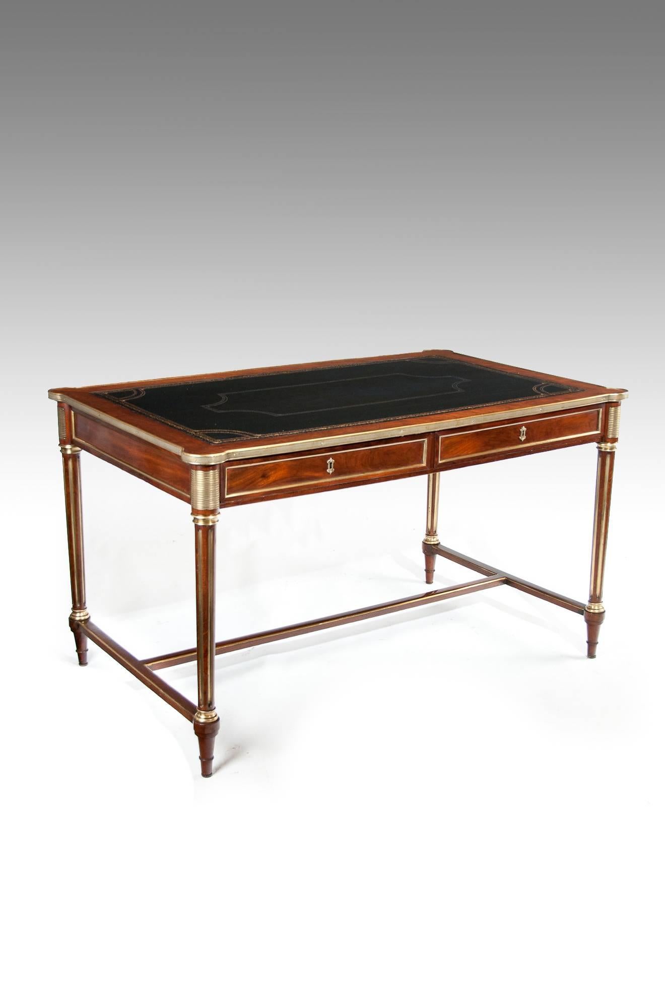A very elegant and fine quality French mahogany and brass bound two drawer writing table with H framed stretcher in the Louis XVI manner, circa 1860-1870
The rectangular top with shaped corners having a newly fitted dark navy gilt and blind tooled