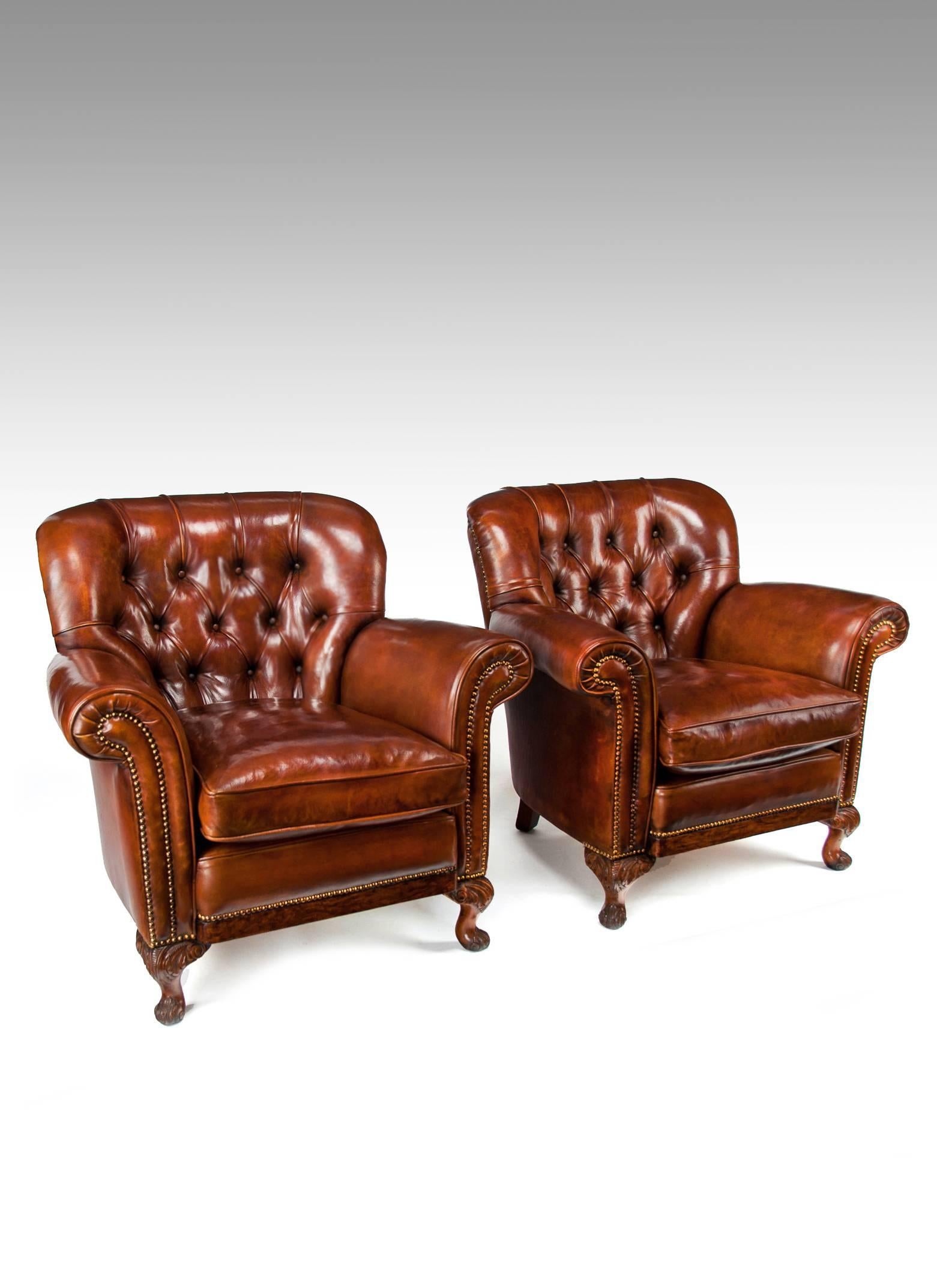 A very handsome pair of antique leather upholstered walnut shaped armchairs on carved cabriole legs dating to circa 1910-1920.
These very well drawn pair of armchairs have a very comfortable feathered cushion seat and a shaped back. 
Of elegant form
