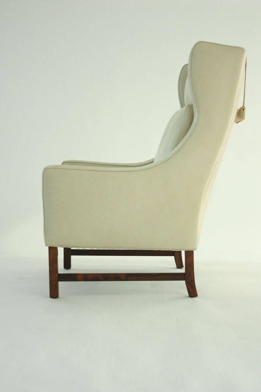Scandinavian Modern high back lounge chair with weighted strap headrest cushion. Rosewood and leather upholstery, circa 1960s. Recently reupholstered. Rosewood frame is in very good condition. Overall very good condition.
 