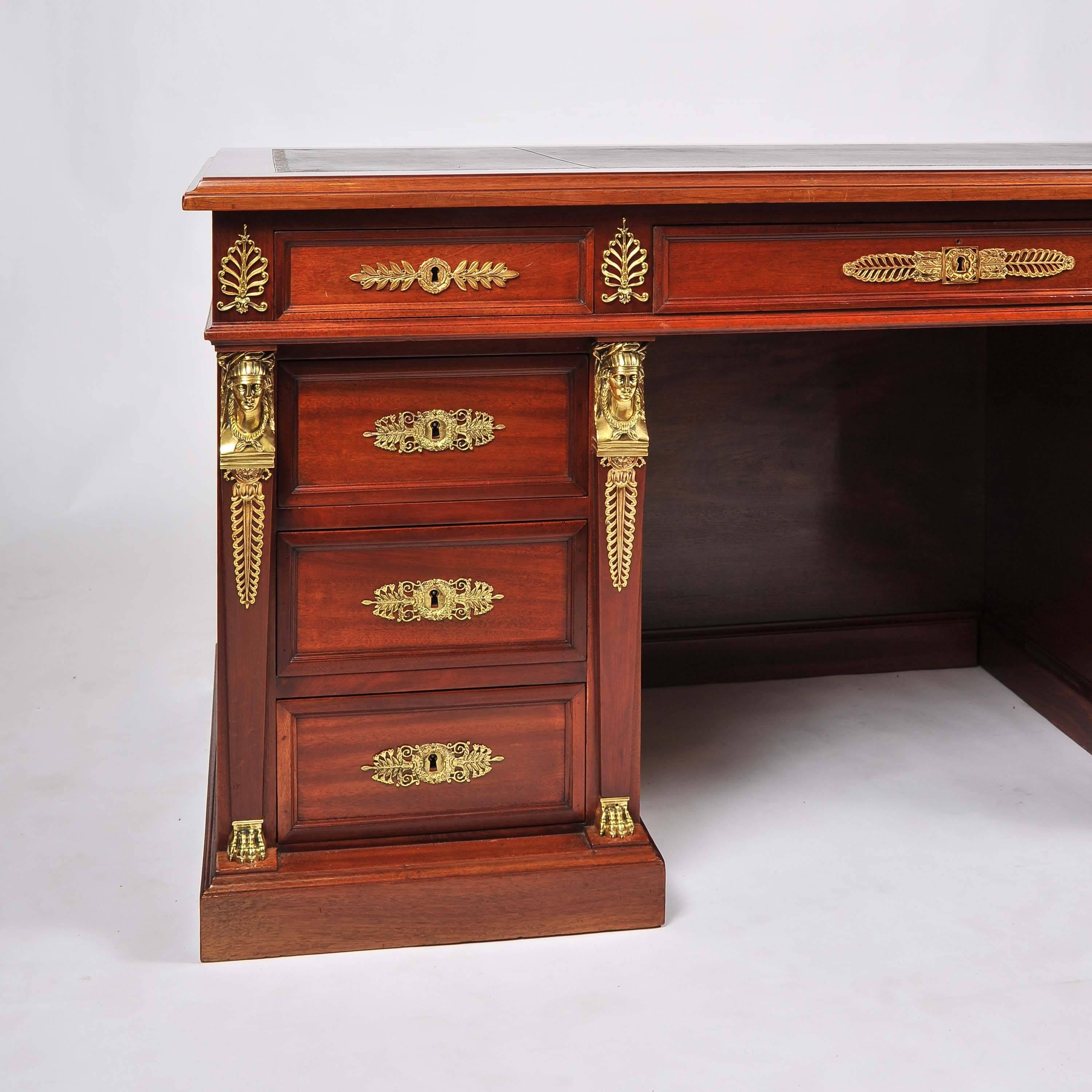 A fine French late 19th century mahogany and ormolu pedestal desk with tooled leather top in the Empire style, having nine drawers, one containing a locking secret compartment, with two secretary writing slides to either side of top.