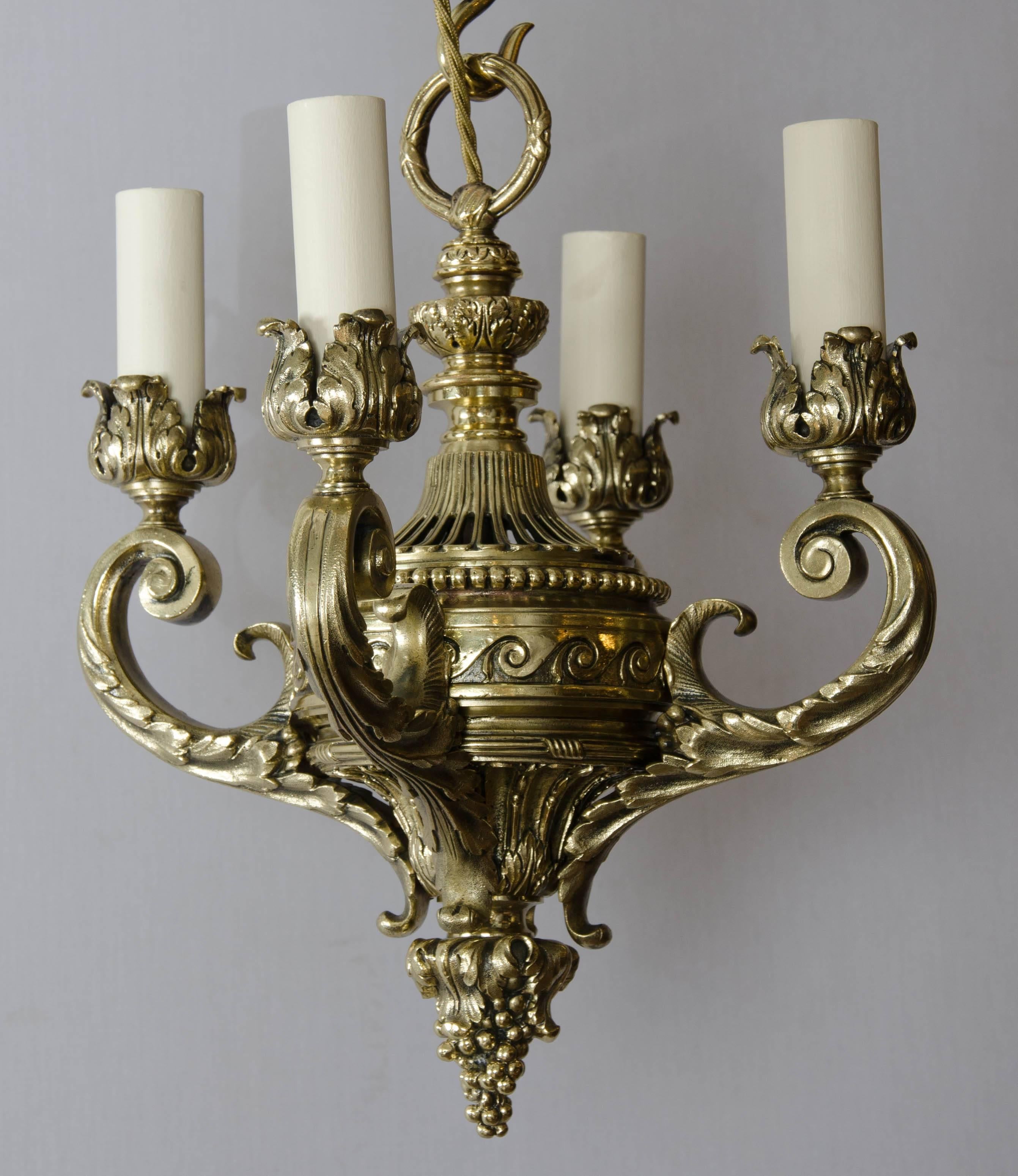 A small-scale brass four-arm chandelier in the Palladian style with Vitruvian scroll motif and chased decoration.

Wired for electricity.

Measures: Height with chain 21 inches.