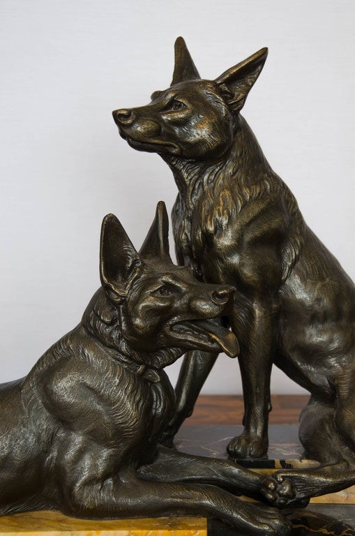 A patinated spelter sculpture of two Alsatians/German Shepherds, on a marble base, titled 