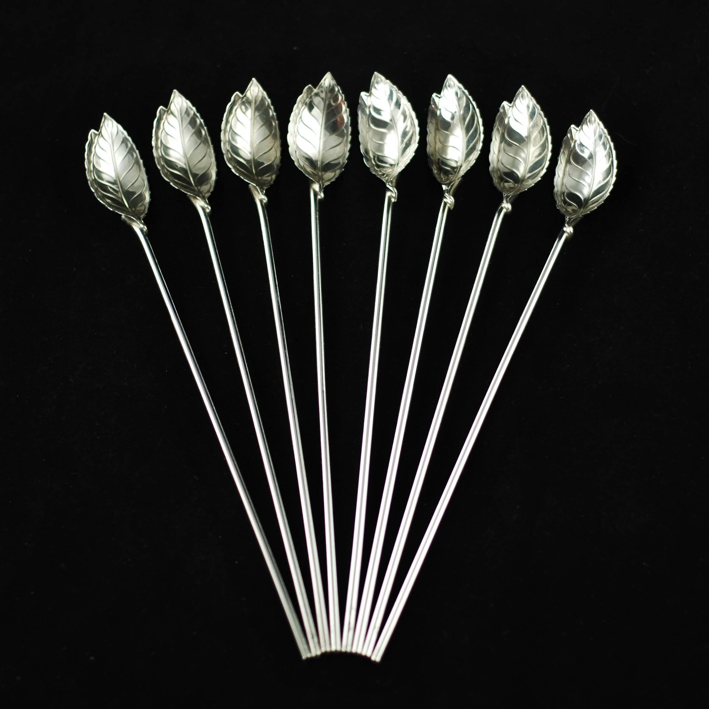 This set of eight mint julep spoons / straws was made by Tiffany & Company. The pieces are composed of sterling silver with bowls that have been cast in the form of realistic mint leaves with serrated edges. The long thin handles are hollow and also