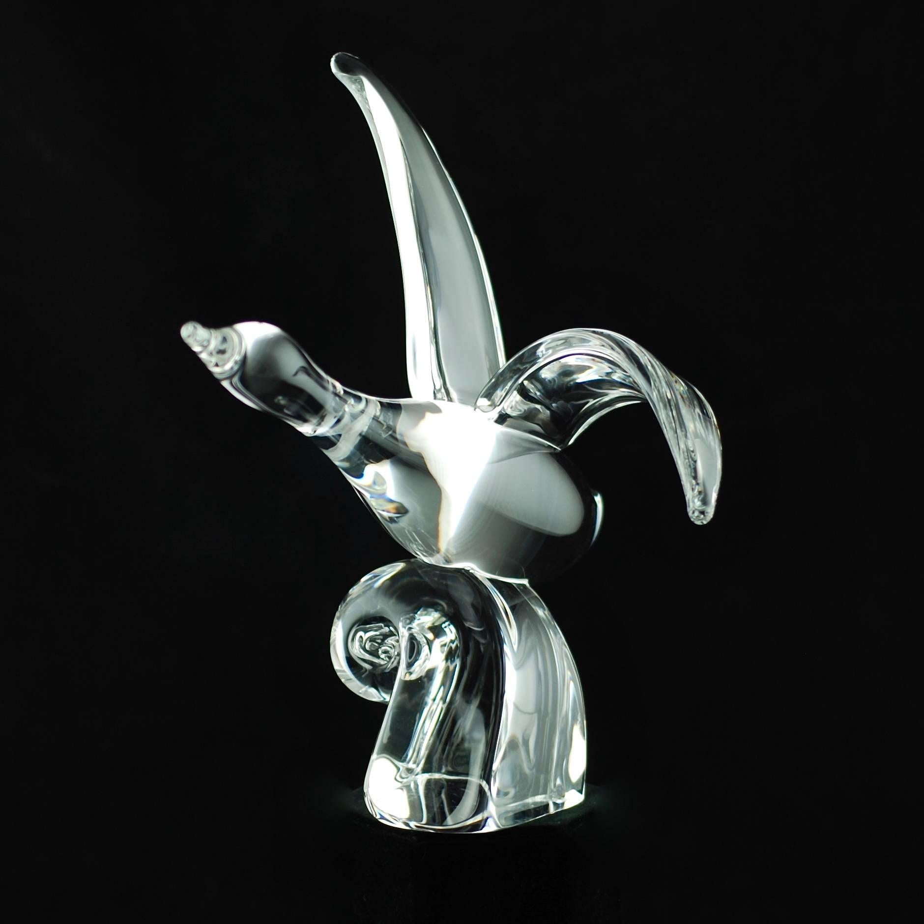 This sleek crystal bird was designed by noted Steuben glass staff designer Lloyd Atkins and depicts a water fowl on an upward trajectory with its wings extended and body skimming the top of a wave. There is an elegant symmetry to the piece with the