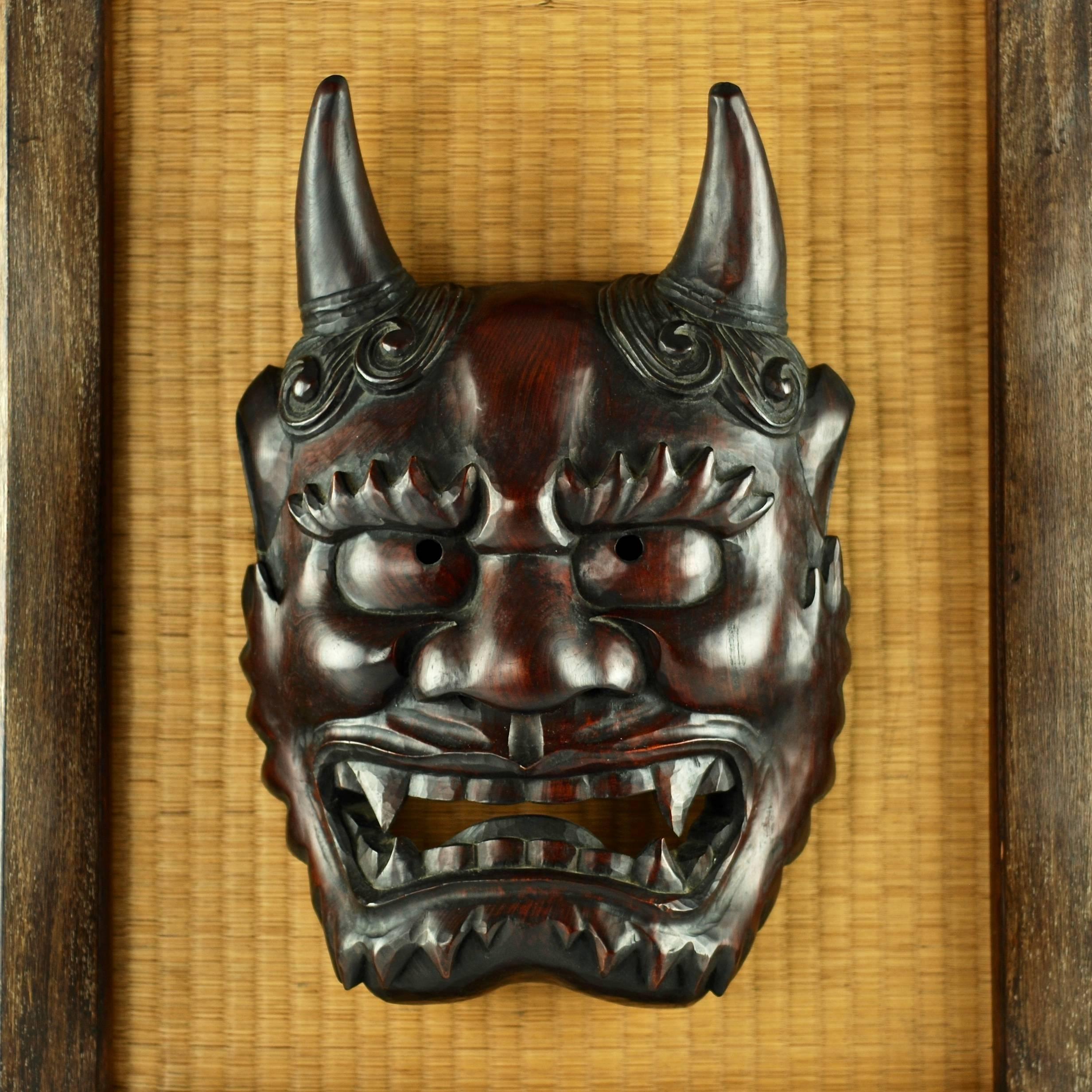This oversize hand-carved wooden Japanese Noh theatrical mask depicts the character Hannya, a female who was betrayed and subsequently transformed by jealous rage into demon form. The Hannya mask has a characteristic appearance with two pointed