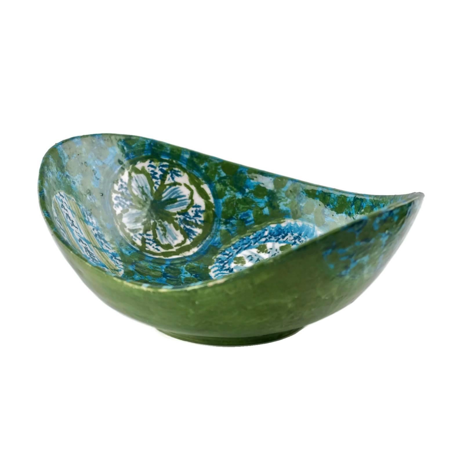 Diese ungewöhnliche Keramikschale wurde in Italien für den amerikanischen Importeur Raymor hergestellt. Das Stück hat eine längliche Schaufelform und wurde in Blau- und Grüntönen handbemalt. Das schwammige Innere weist sechs eiförmige Formen auf,