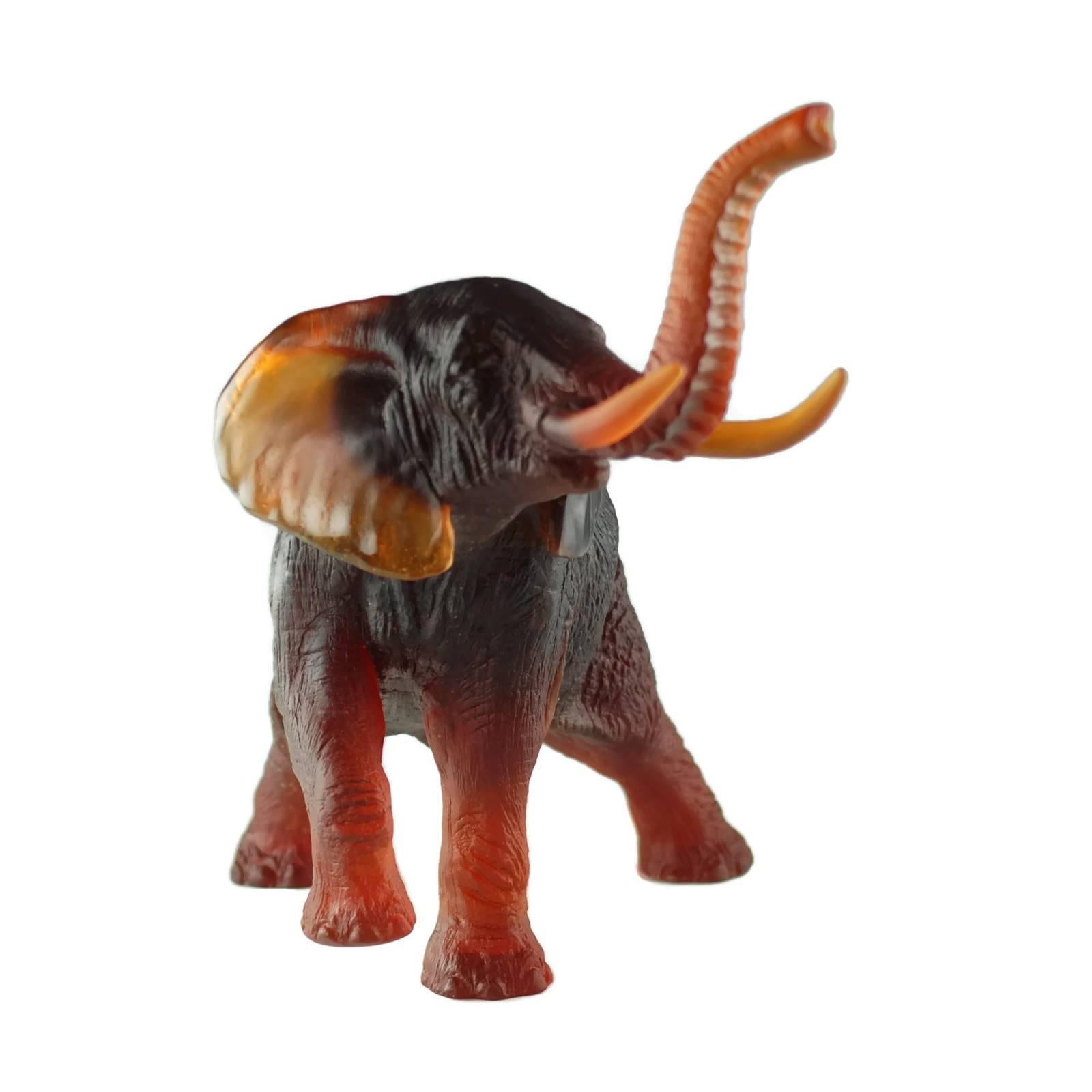 This large figural elephant was designed by sculptor Jean-Francois Leroy for Daum France. The piece is composed of amber pâte de verre glass and depicts an African elephant standing on three legs with trunk raised and mouth open as if in